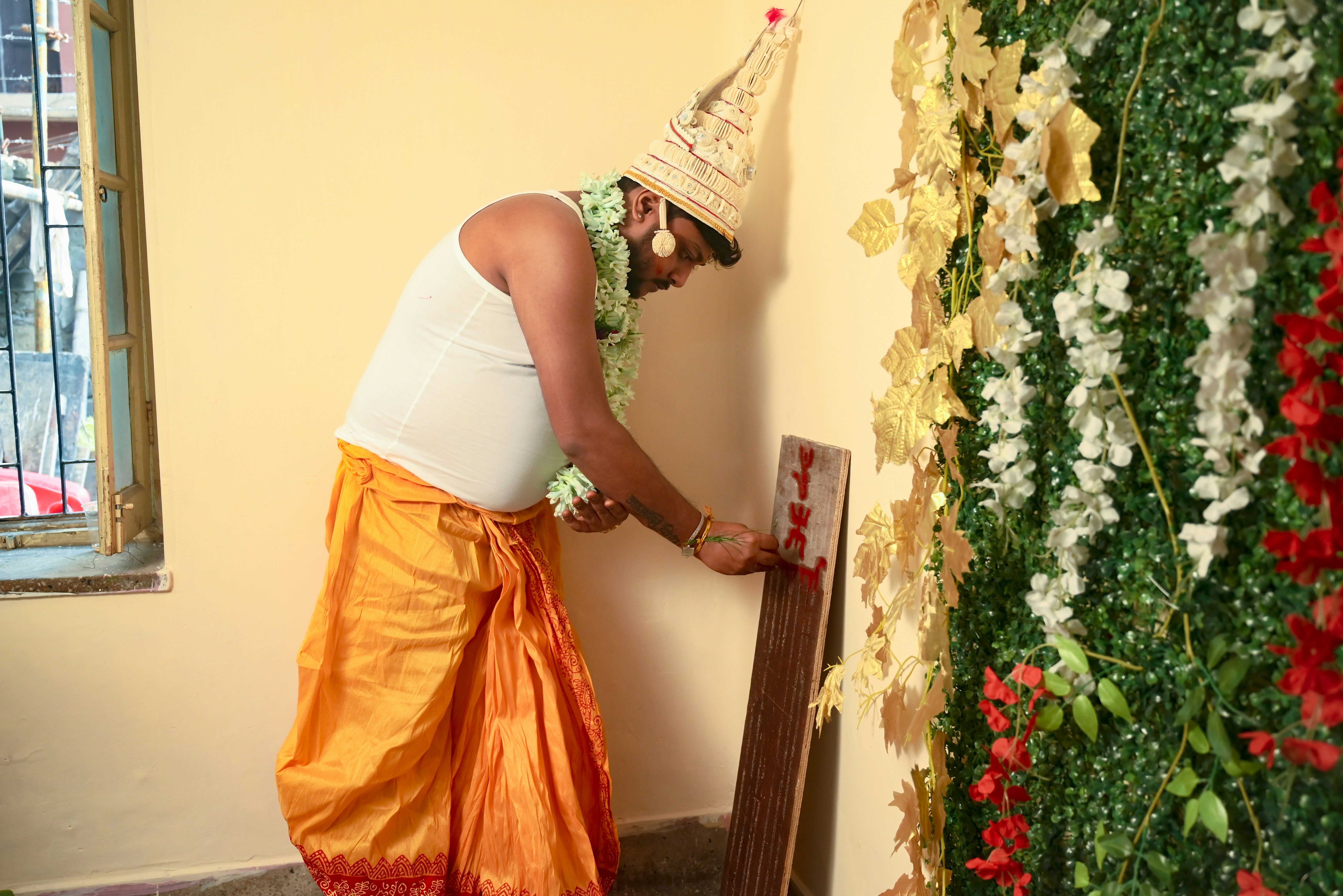 A woman in a party hat painting a wall