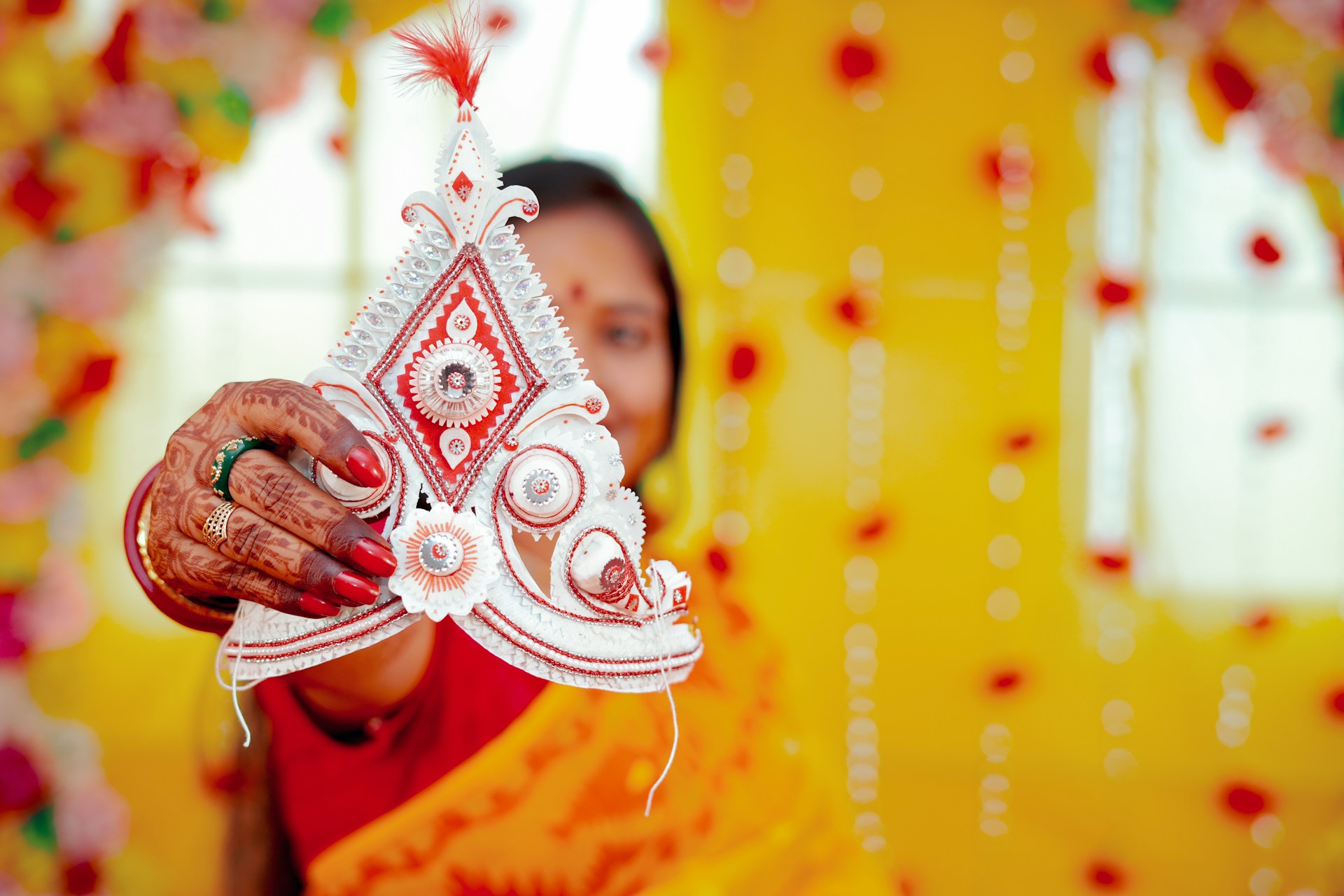 A woman in a red and yellow sari holding a decorative item