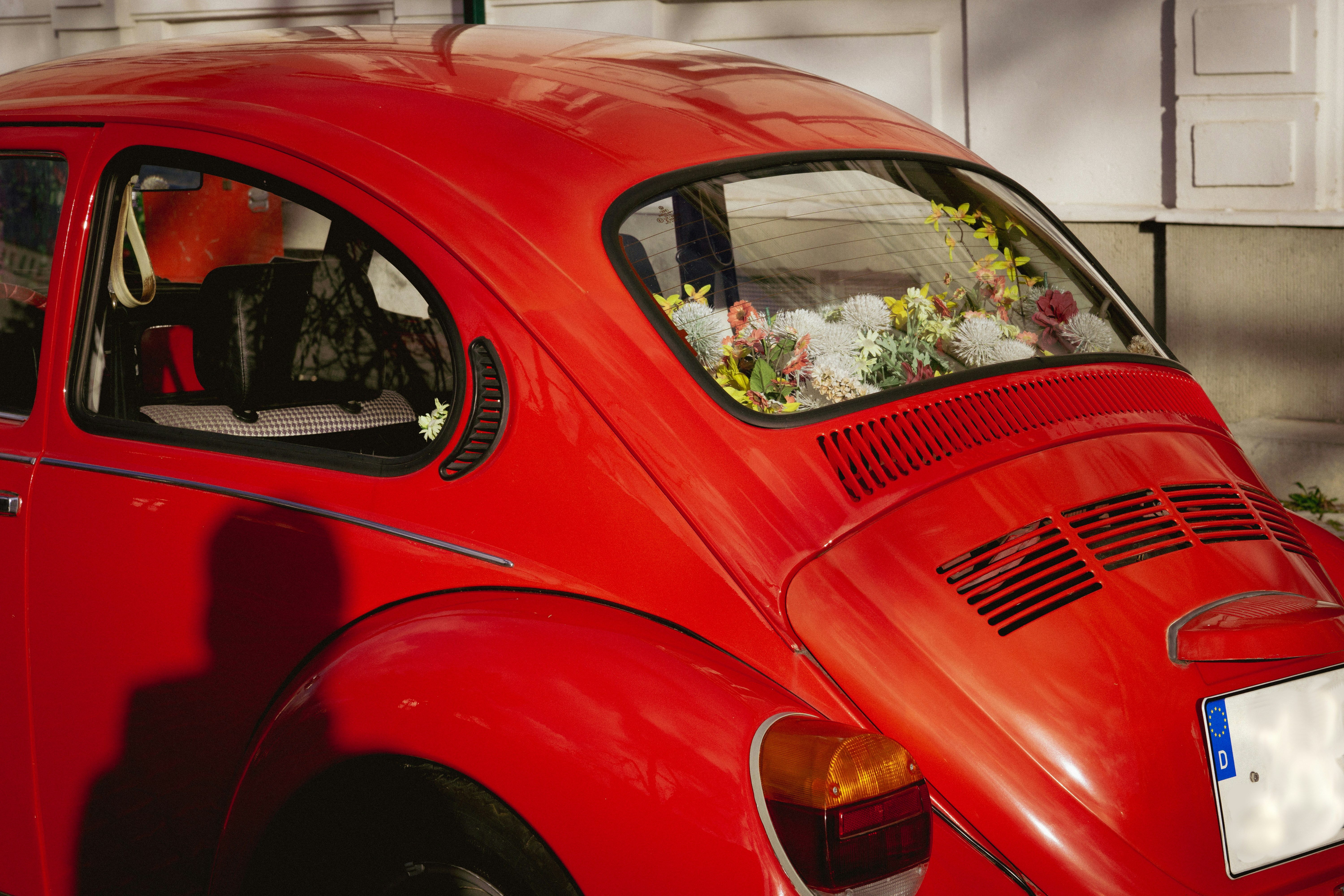 A red car with a bunch of flowers in the back