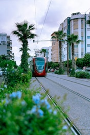 A red train traveling down train tracks next to tall buildings
