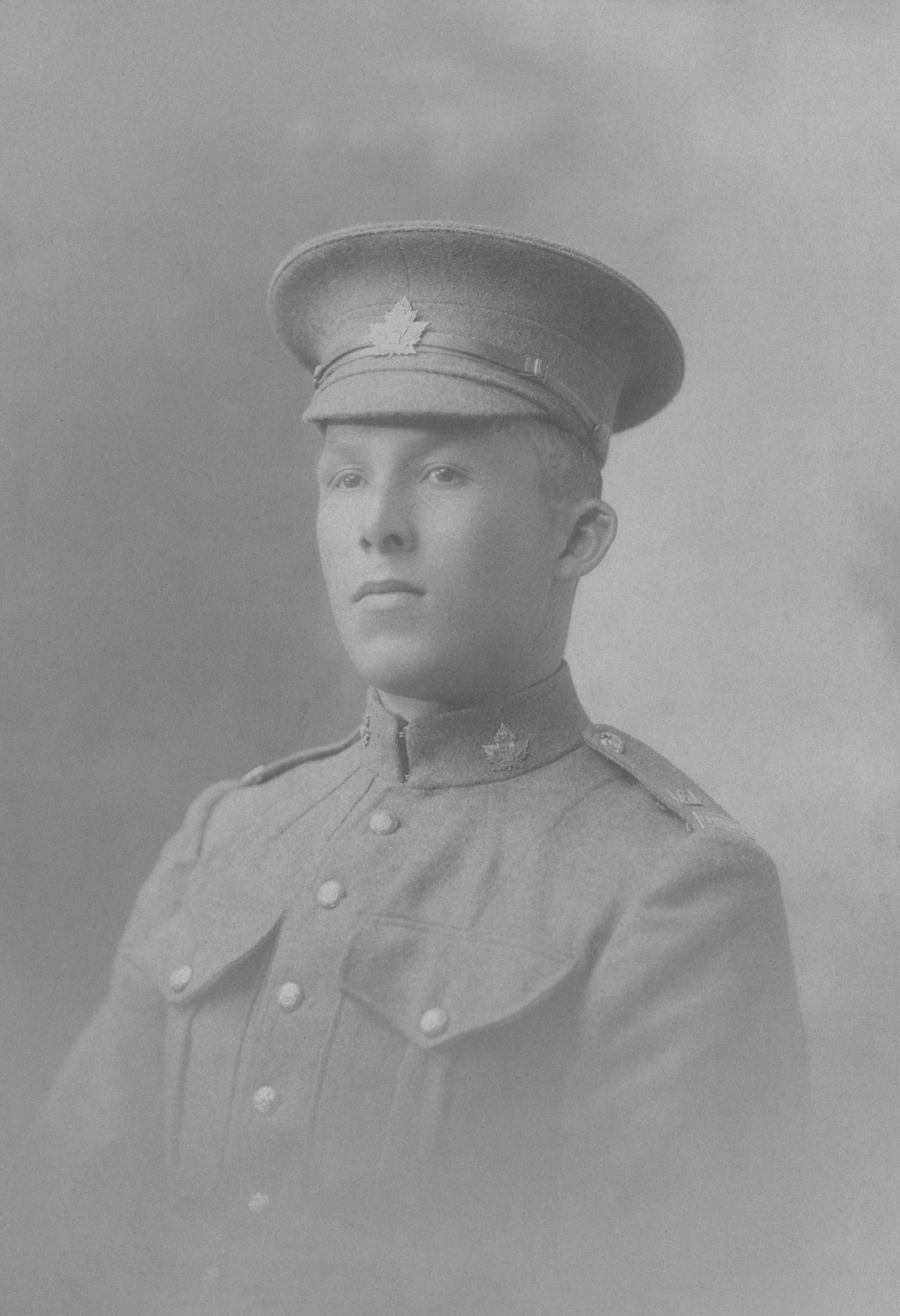A young soldier in uniform looks forward.