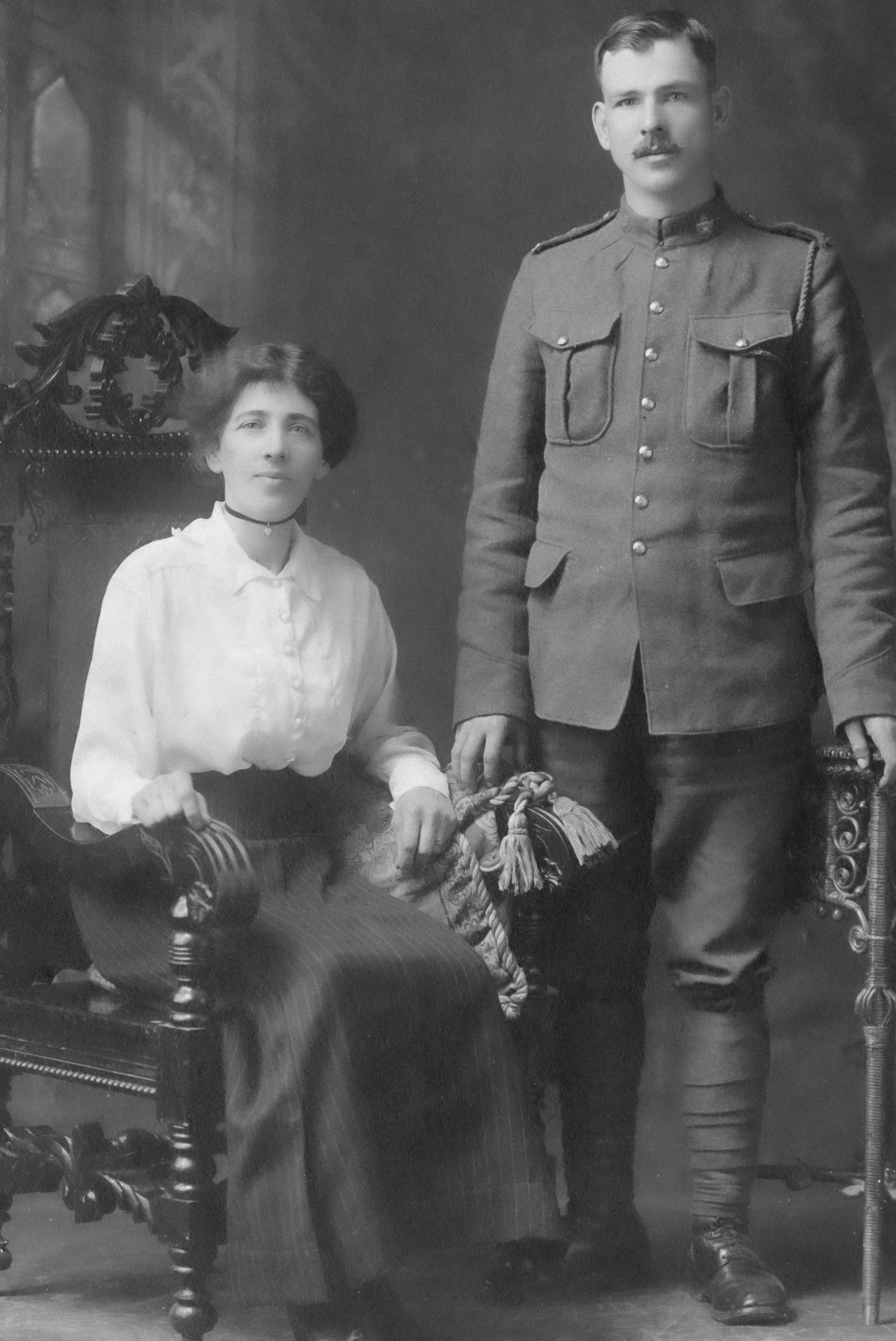 A woman sits next to a soldier in uniform.