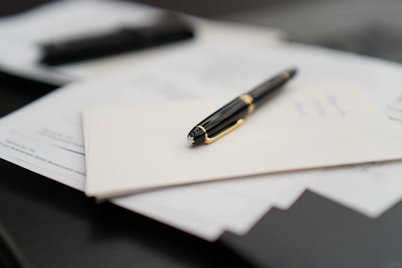 A pen sitting on top of a pile of papers