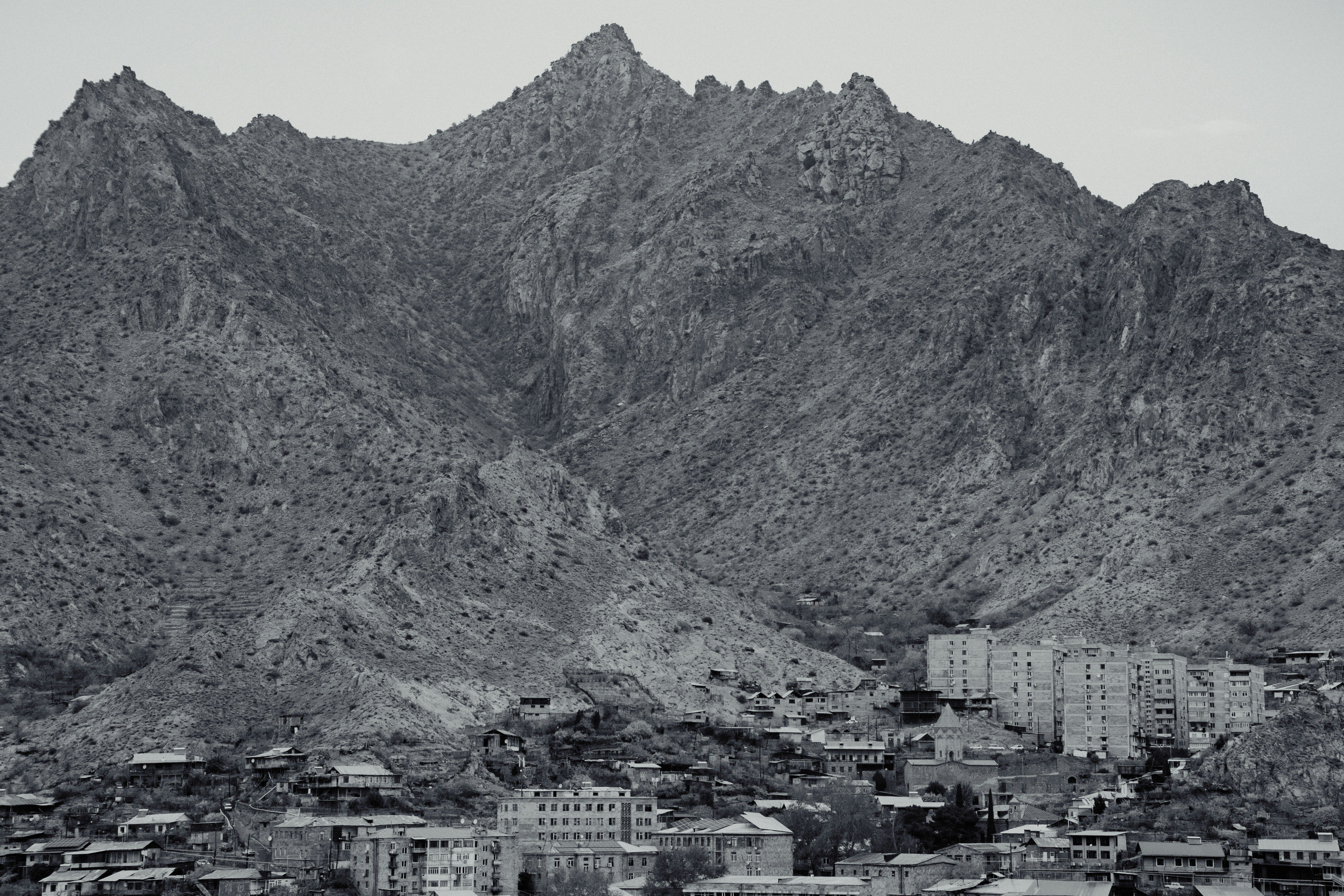 A black and white photo of a city with mountains in the background