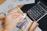 A person is putting money in front of a calculator