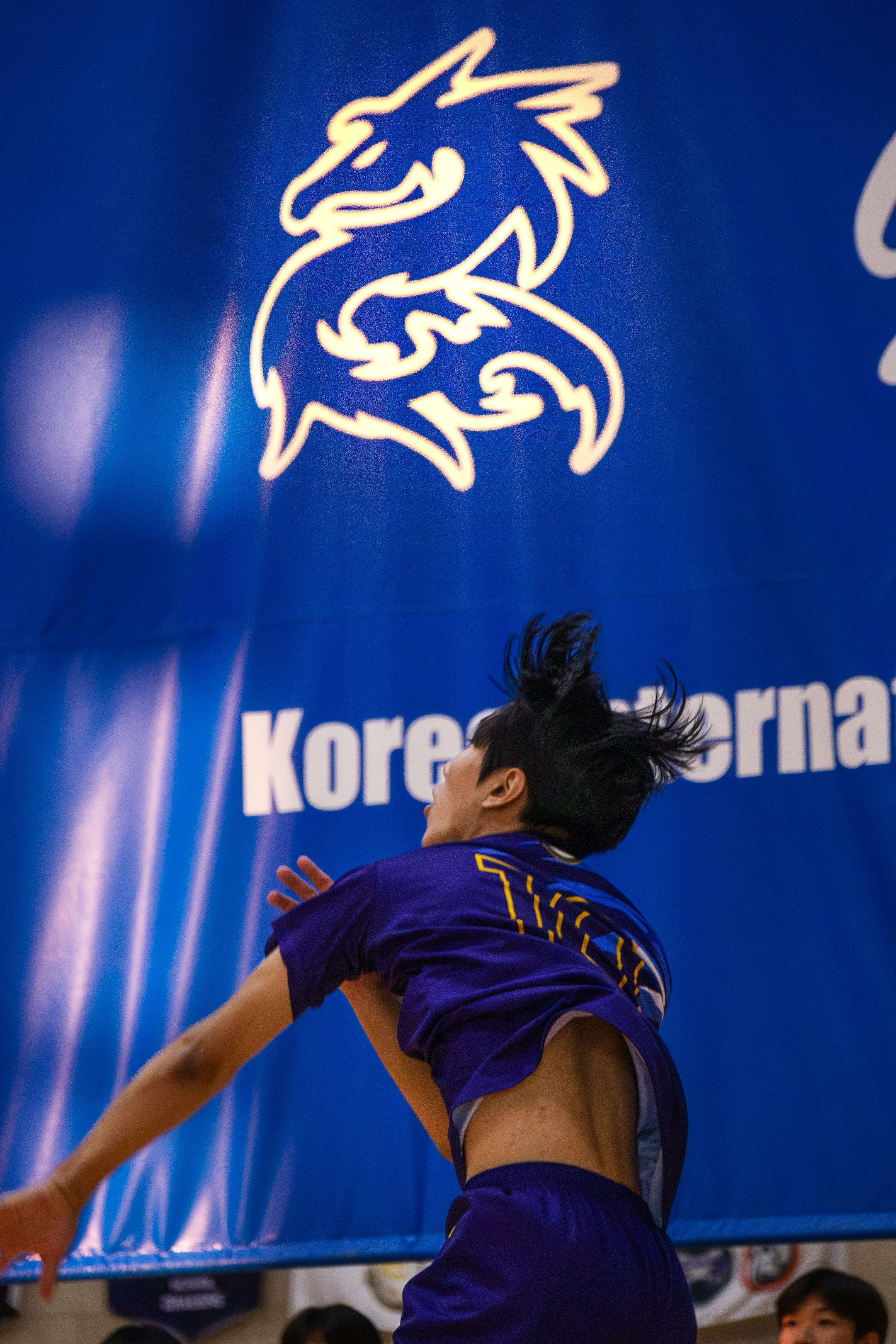 Seorang wanita berseragam ungu melompat untuk memukul bola basket