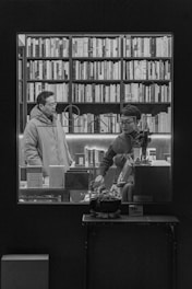 A couple of people standing in front of a book shelf