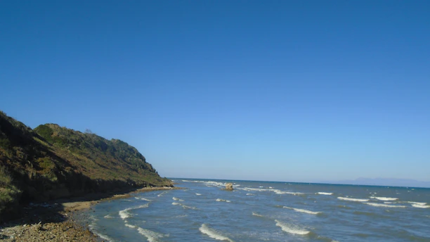 A body of water with a hill in the background