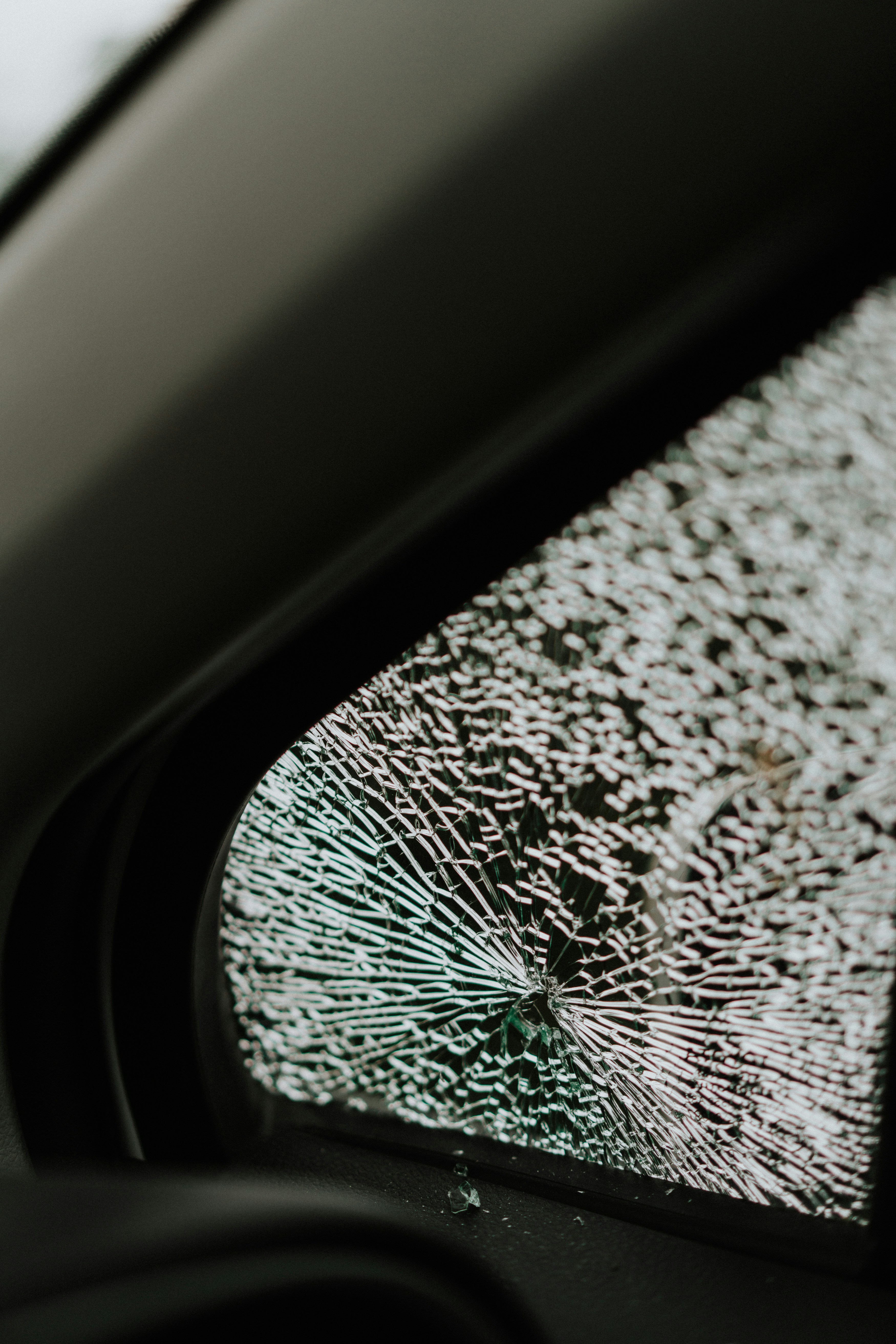 A broken windshield of a car with a broken window