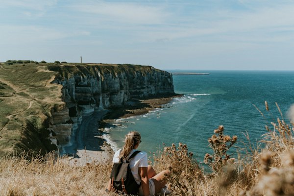 A walker sitting on the clifftop above the sea — Étretat, France