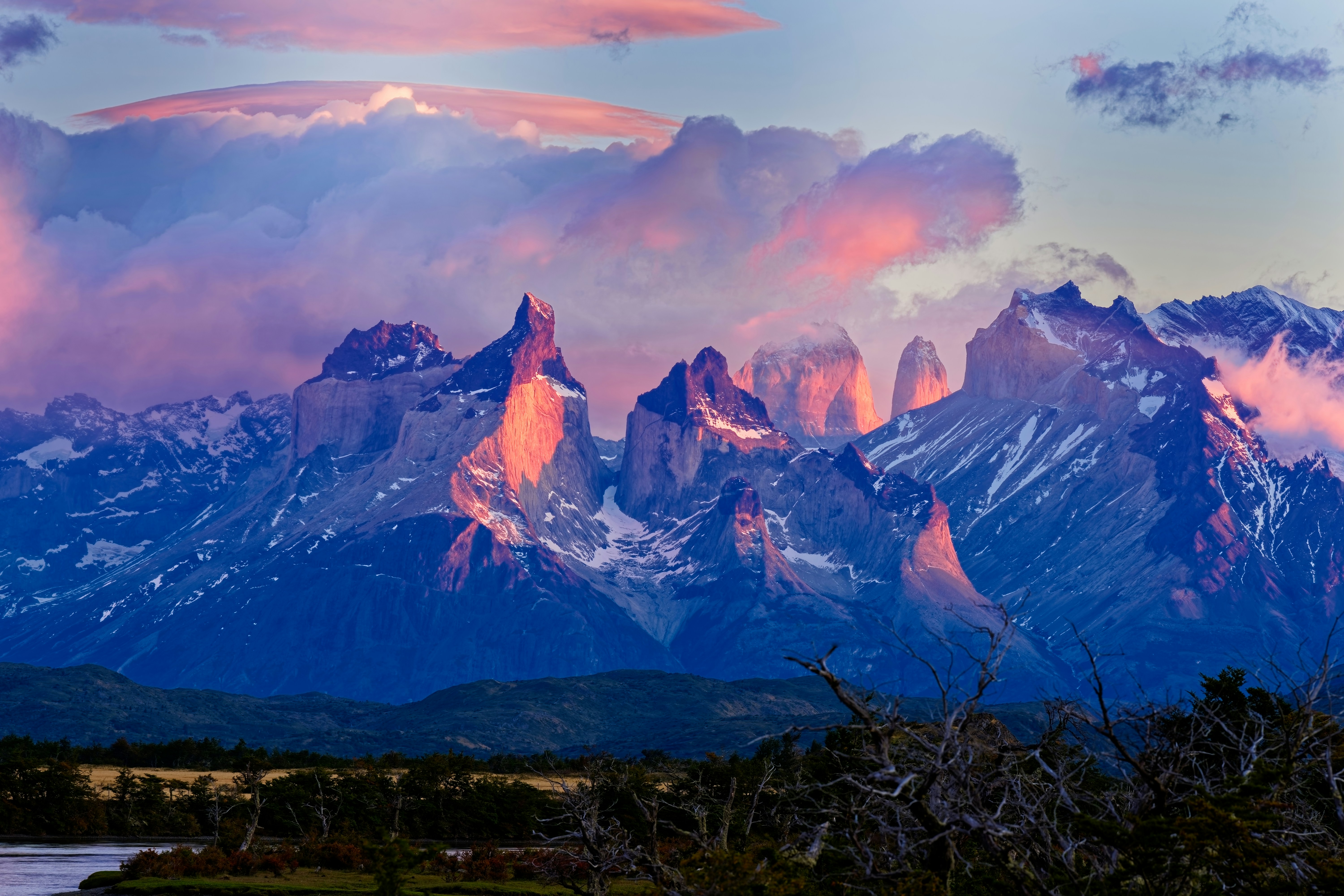 A mountain range with a lake and clouds in the foreground, Sunrise in the dramatic peaks of the Torres del Paine National Park in Chile.