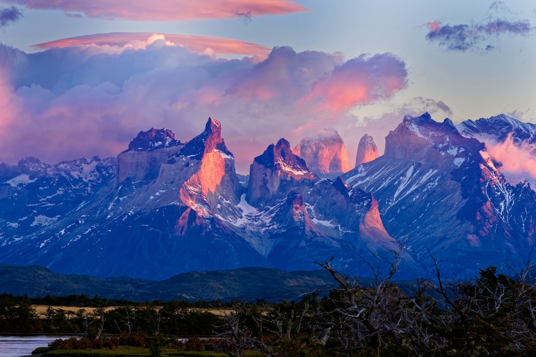 A mountain range with a lake and clouds in the foreground, Sunrise in the dramatic peaks of the Torres del Paine Nationa