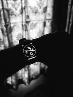 A black and white photo of a person's hand with a watch on it