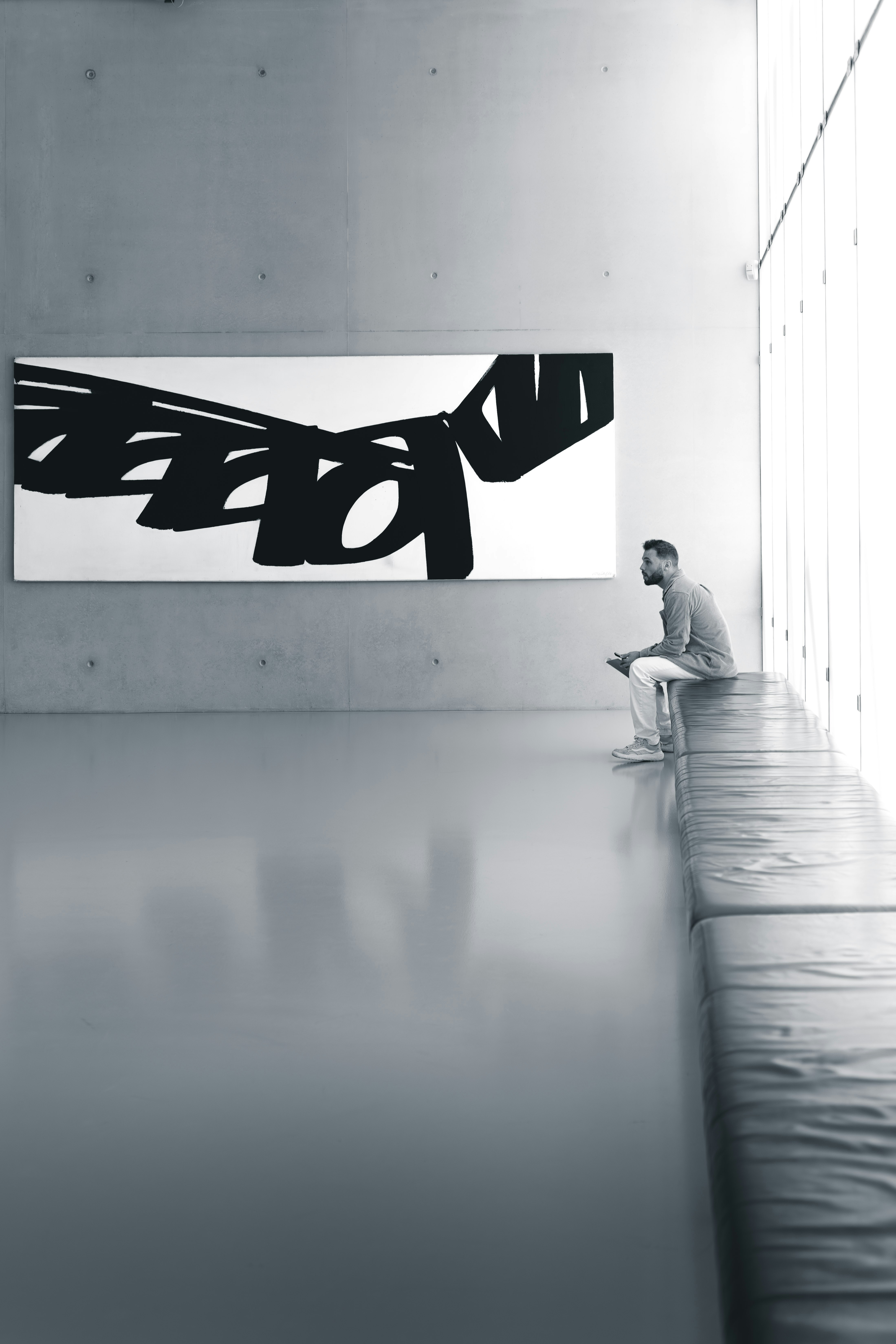 A man sitting on a bench in front of a painting