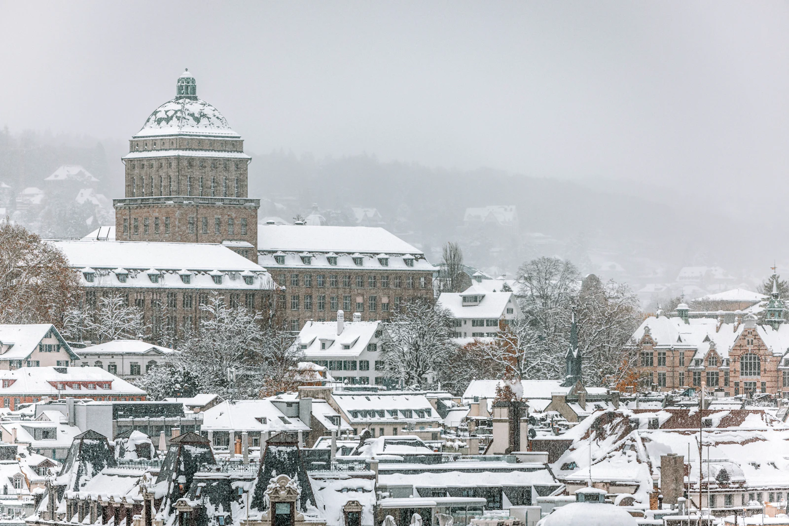 Snowy Zürich old town rooftops with a clock tower in the background