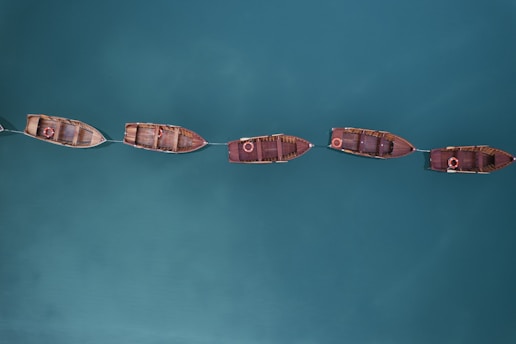 Foto cenital de una fila de botes atados, en la que también se aprecia el azul del mar