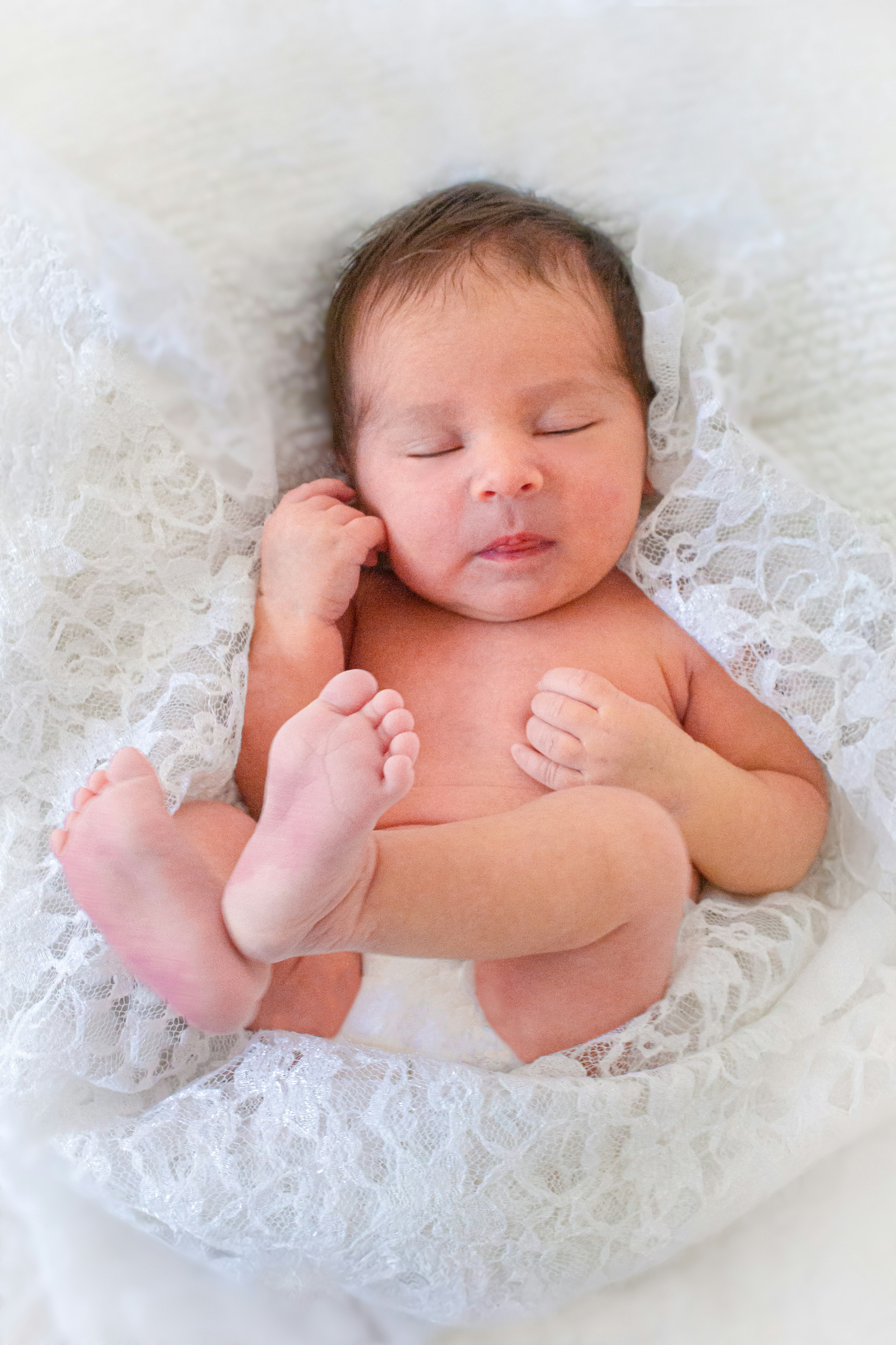 A baby is sleeping on a white blanket