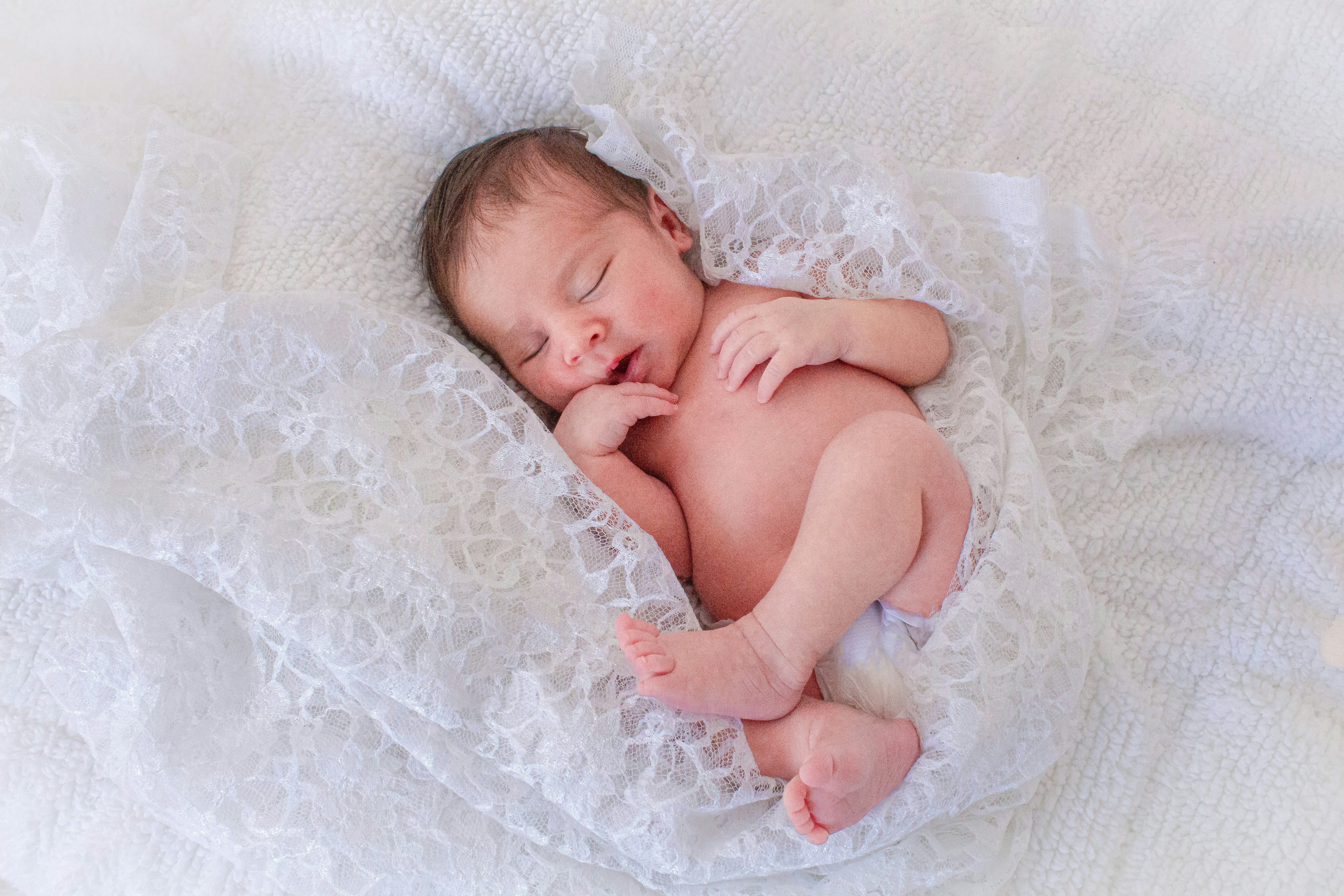 A baby is sleeping on a white blanket