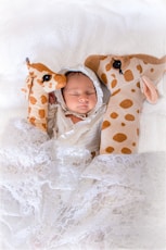 A baby wrapped in a blanket with a giraffe pillow