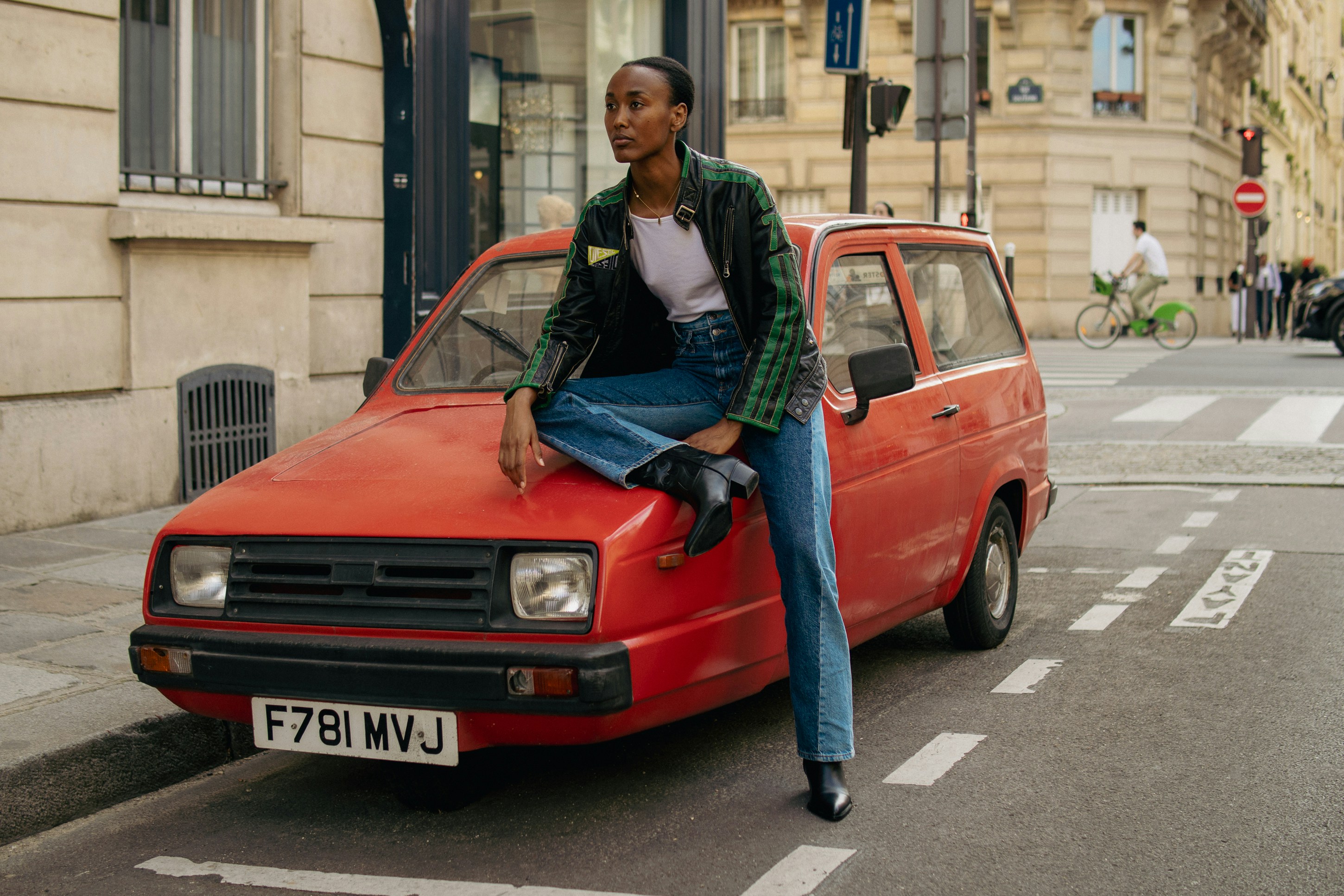 A woman sitting on the hood of a red car