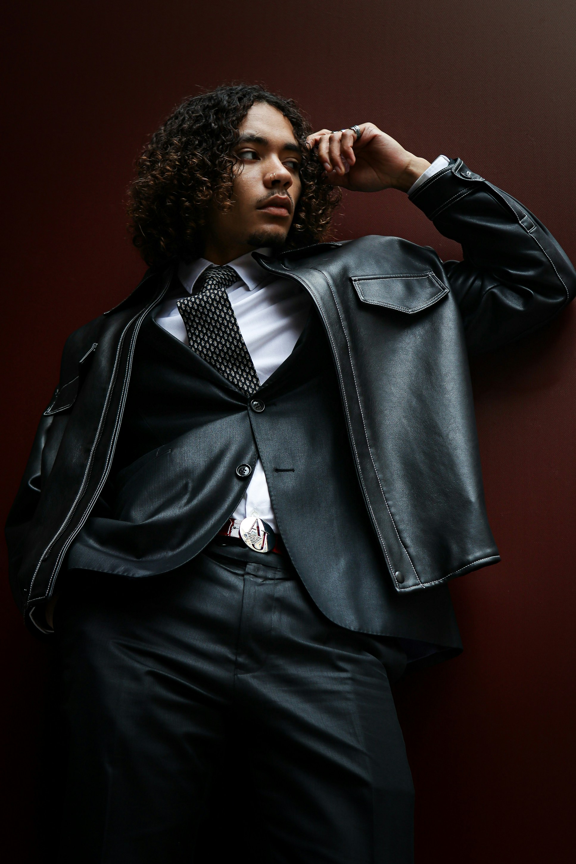A man in a suit and tie leaning against a wall