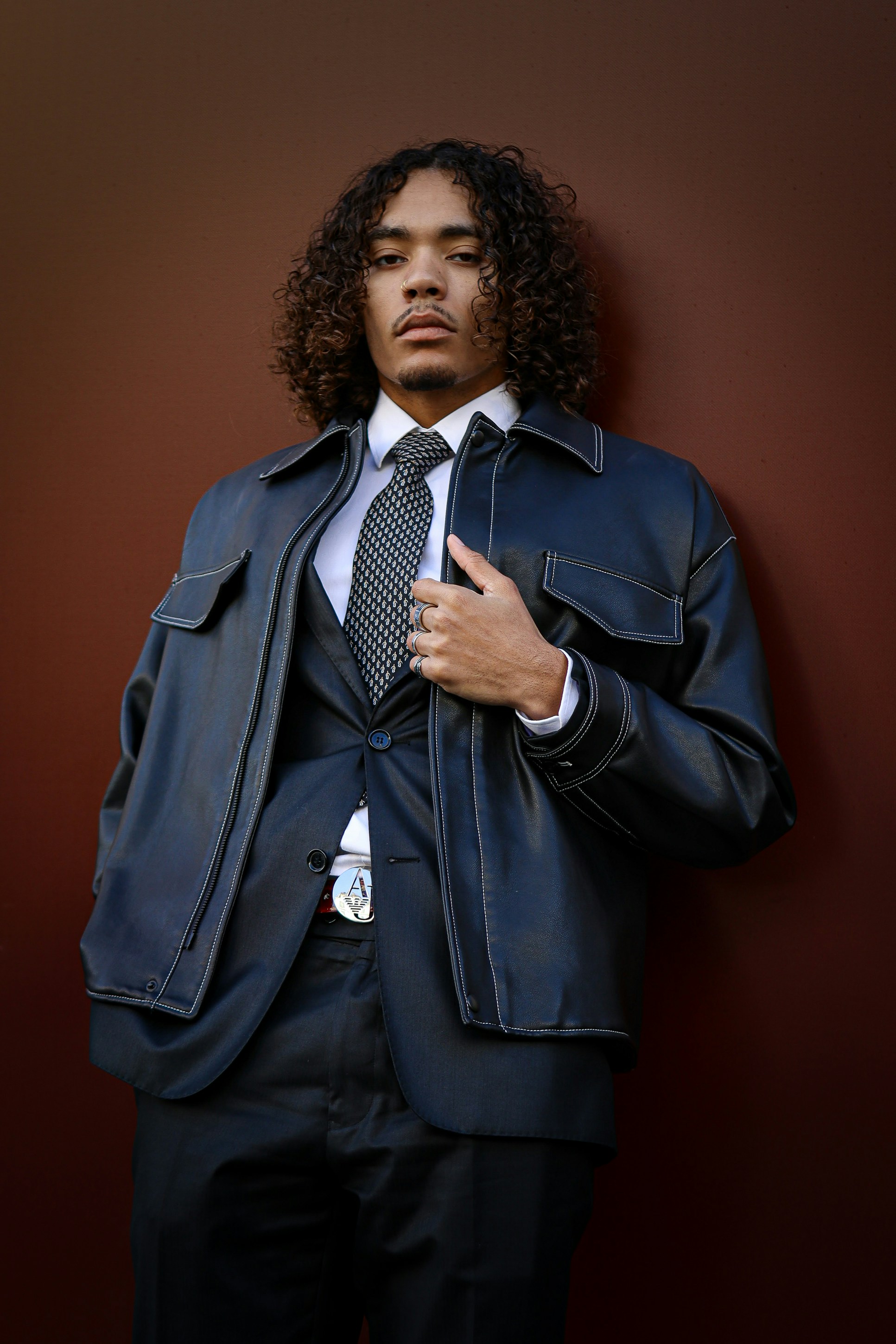 A man in a suit and tie leaning against a wall