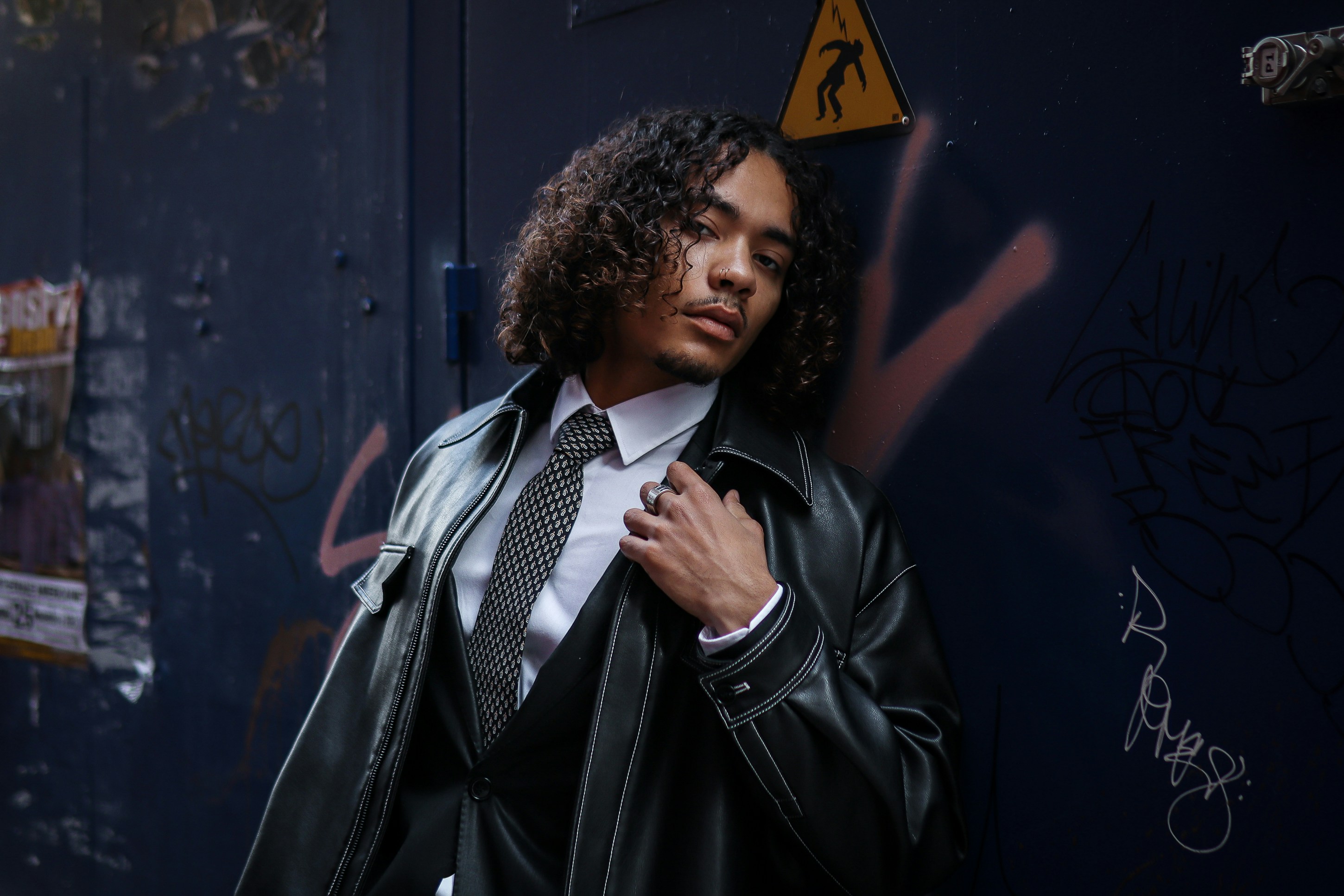 A man standing in front of a wall with graffiti on it