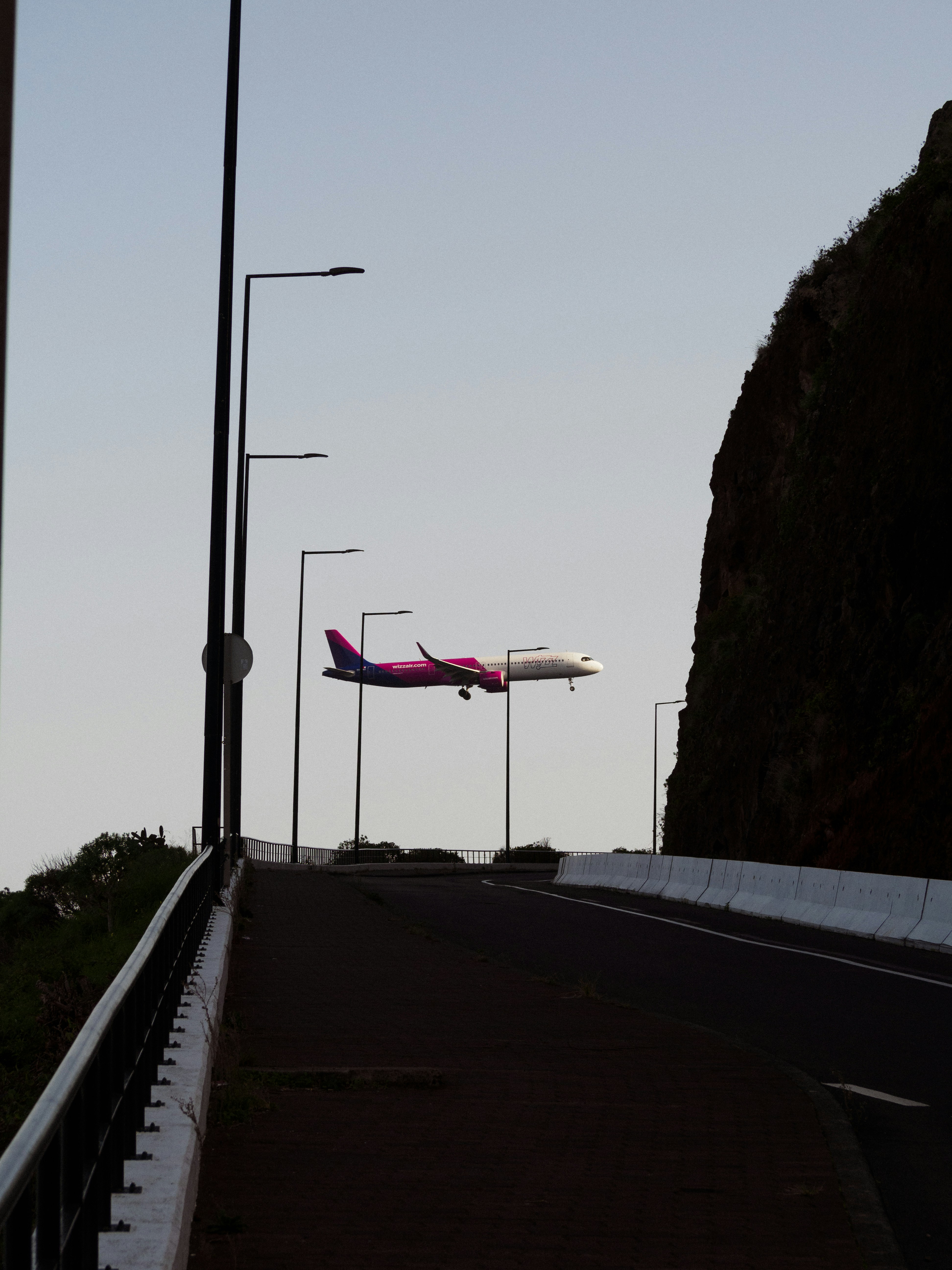 An airplane is flying over a road near a mountain