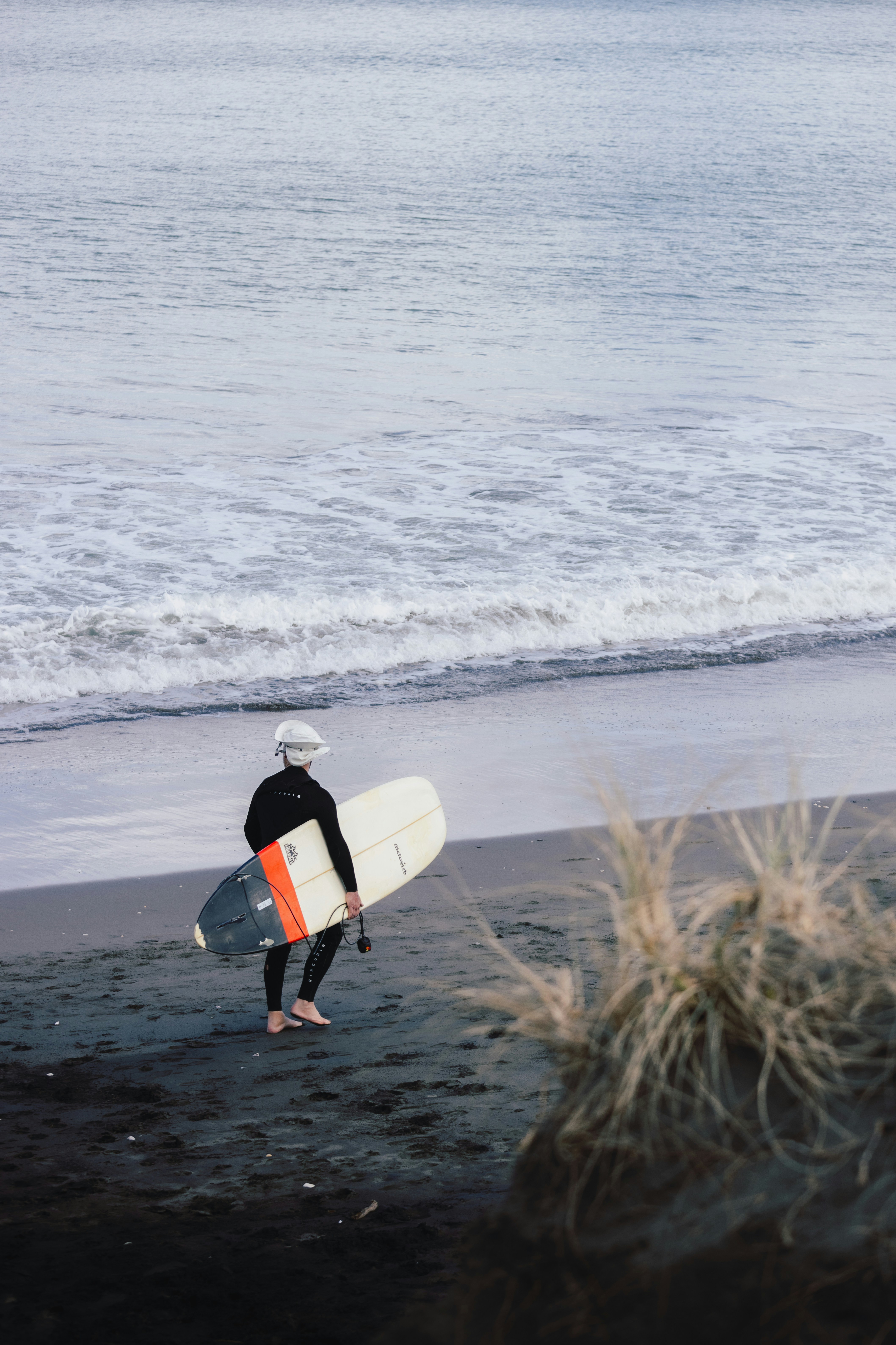 A man holding a surfboard on top of a sandy beach