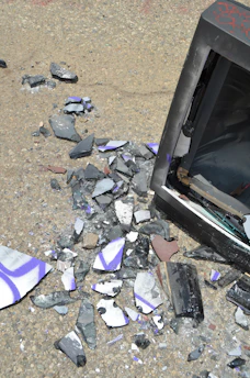 A broken TV sitting on top of a pile of broken glass