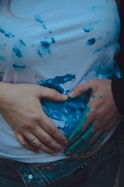 A woman holding her stomach covered in blue paint