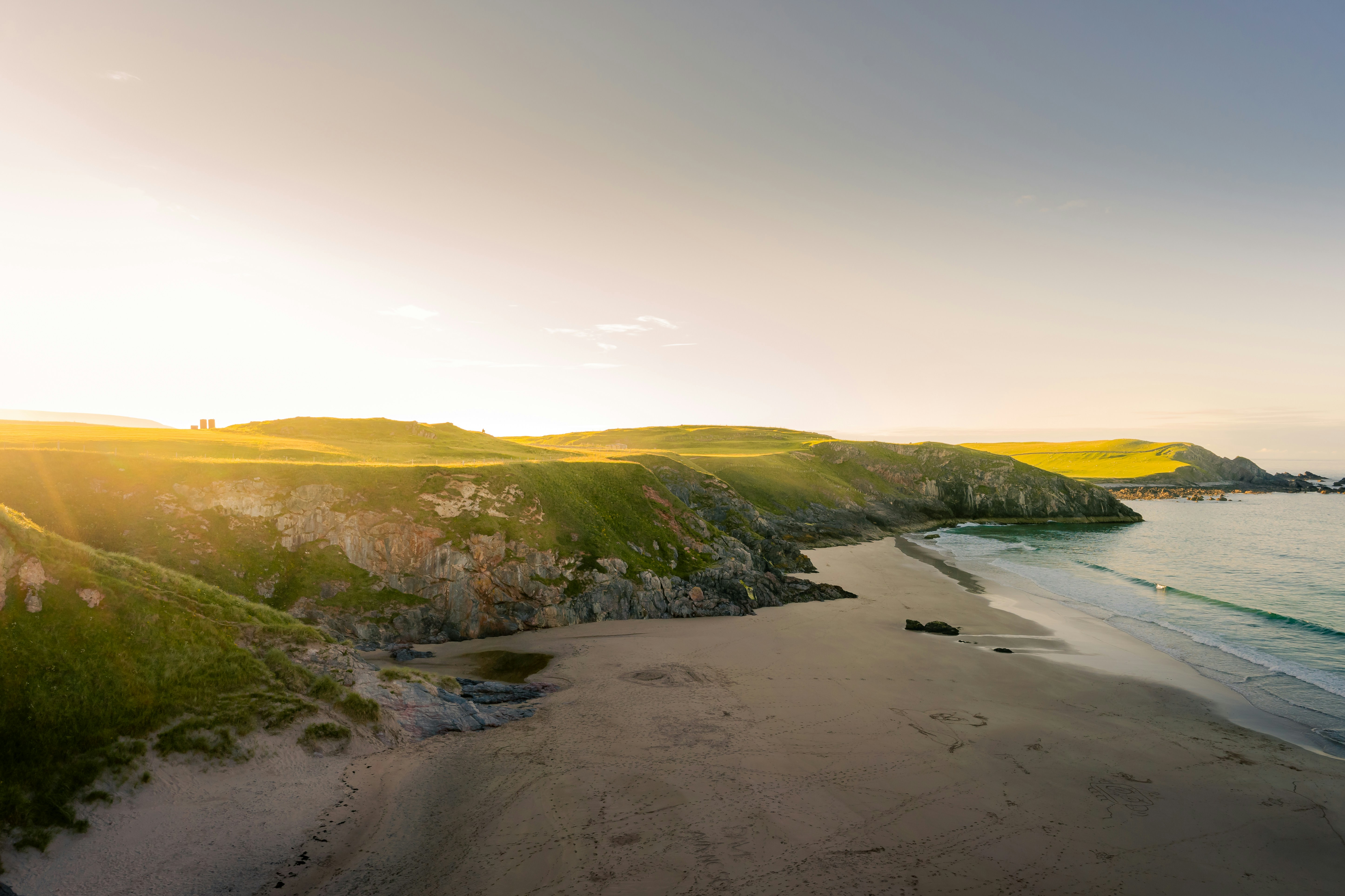 An aerial view of a beach with a cliff in the background