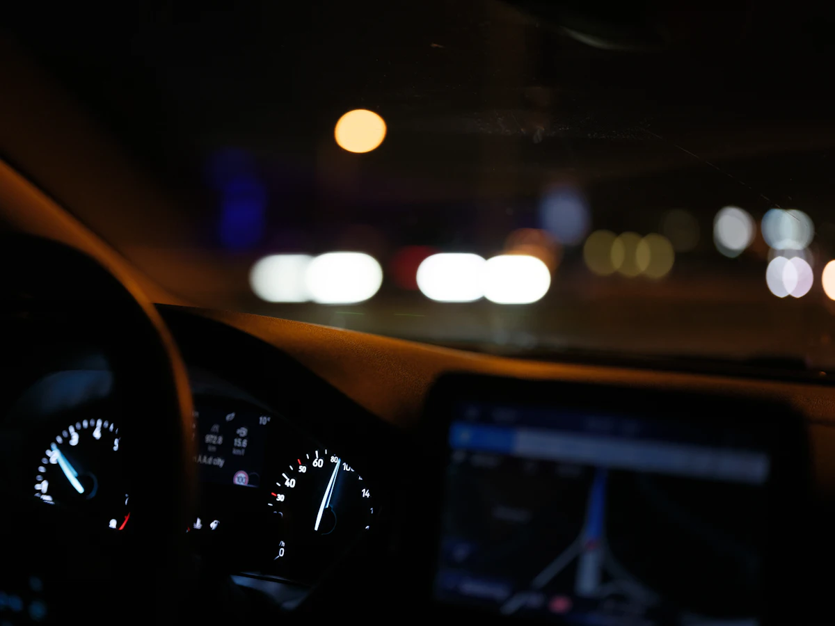 A dashboard at night with lights on the road ahead