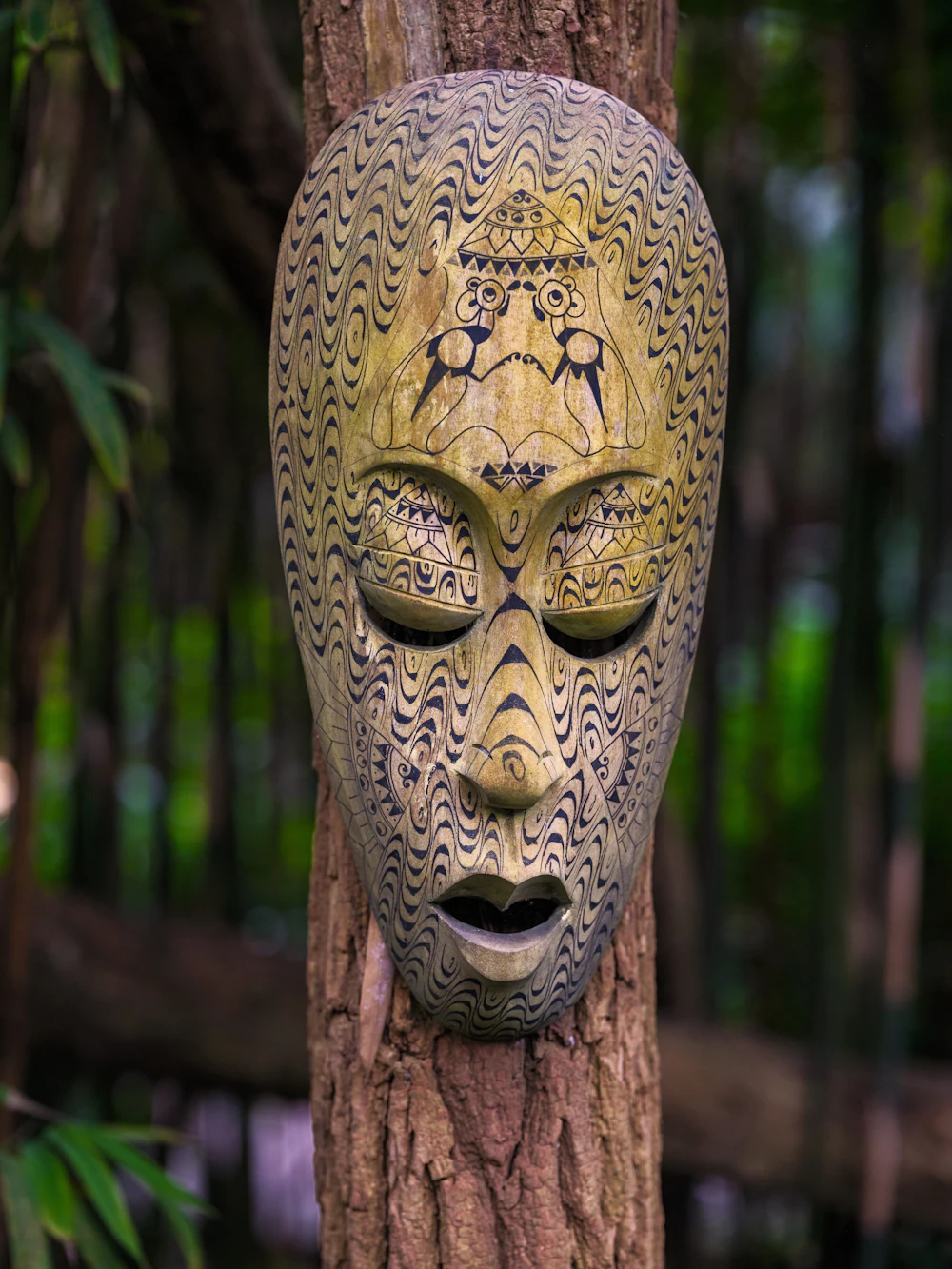 A weathered mask displayed outdoors against natural wood