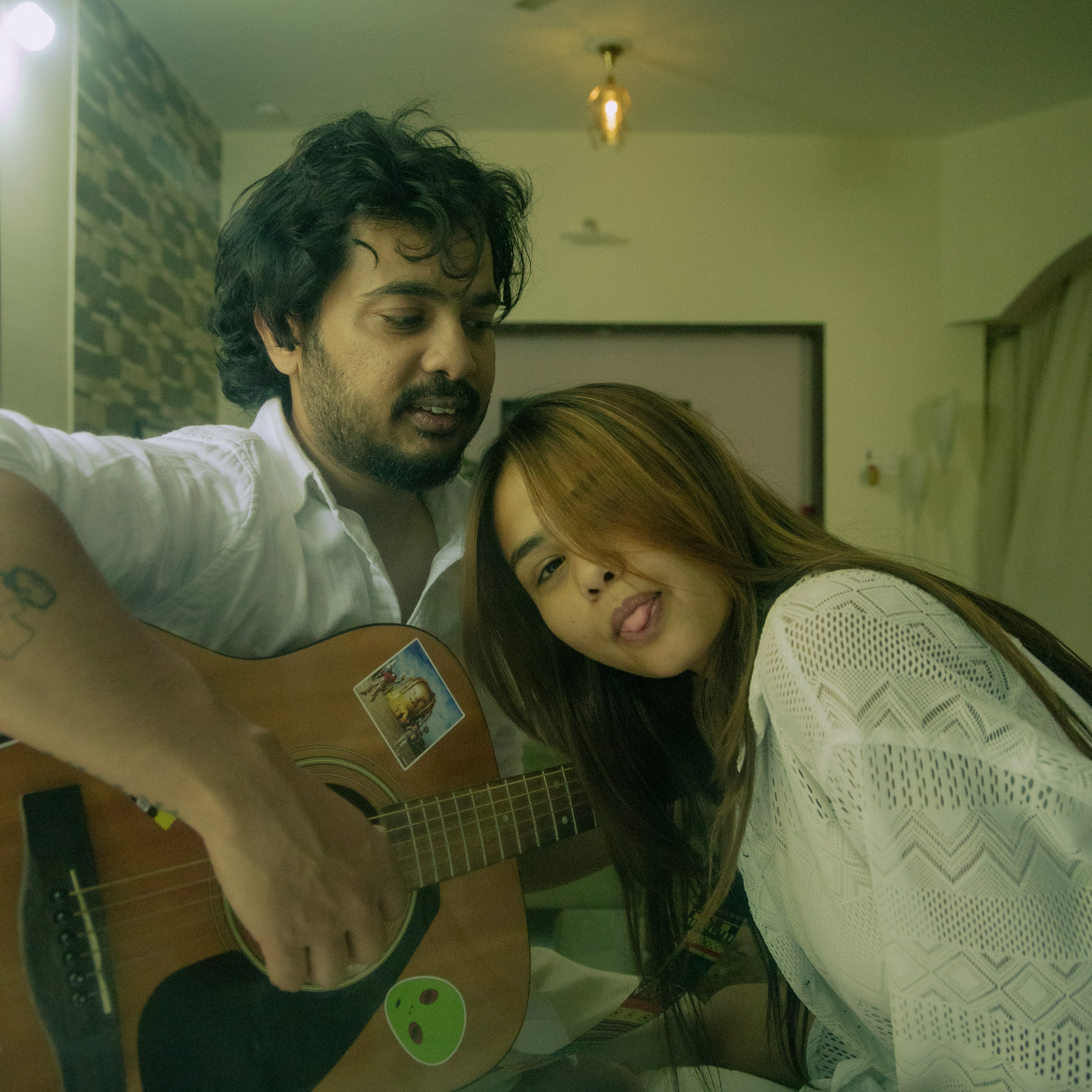 Seorang pria bermain gitar di sebelah seorang wanita