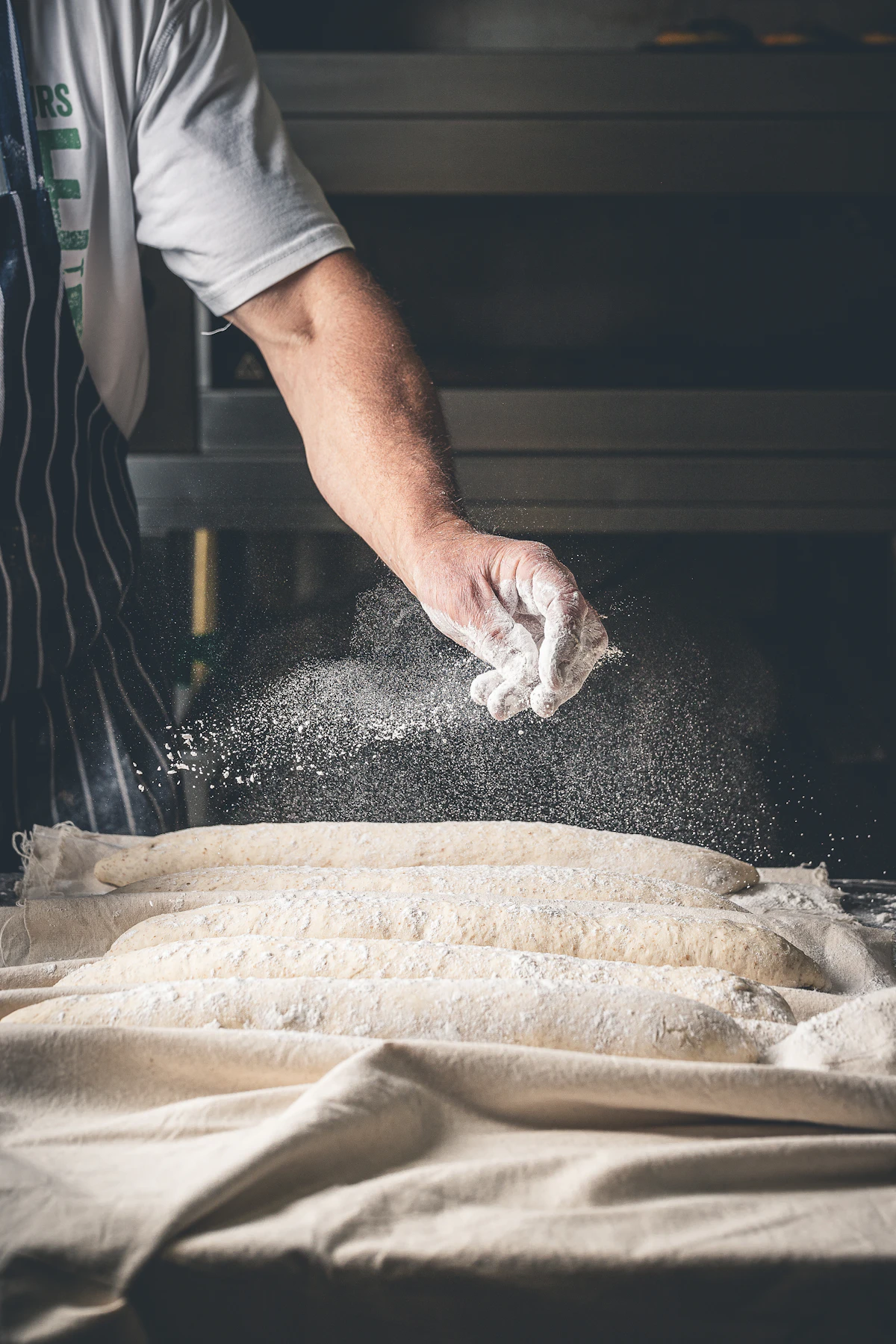 Baker sprinkling flour over rested dough