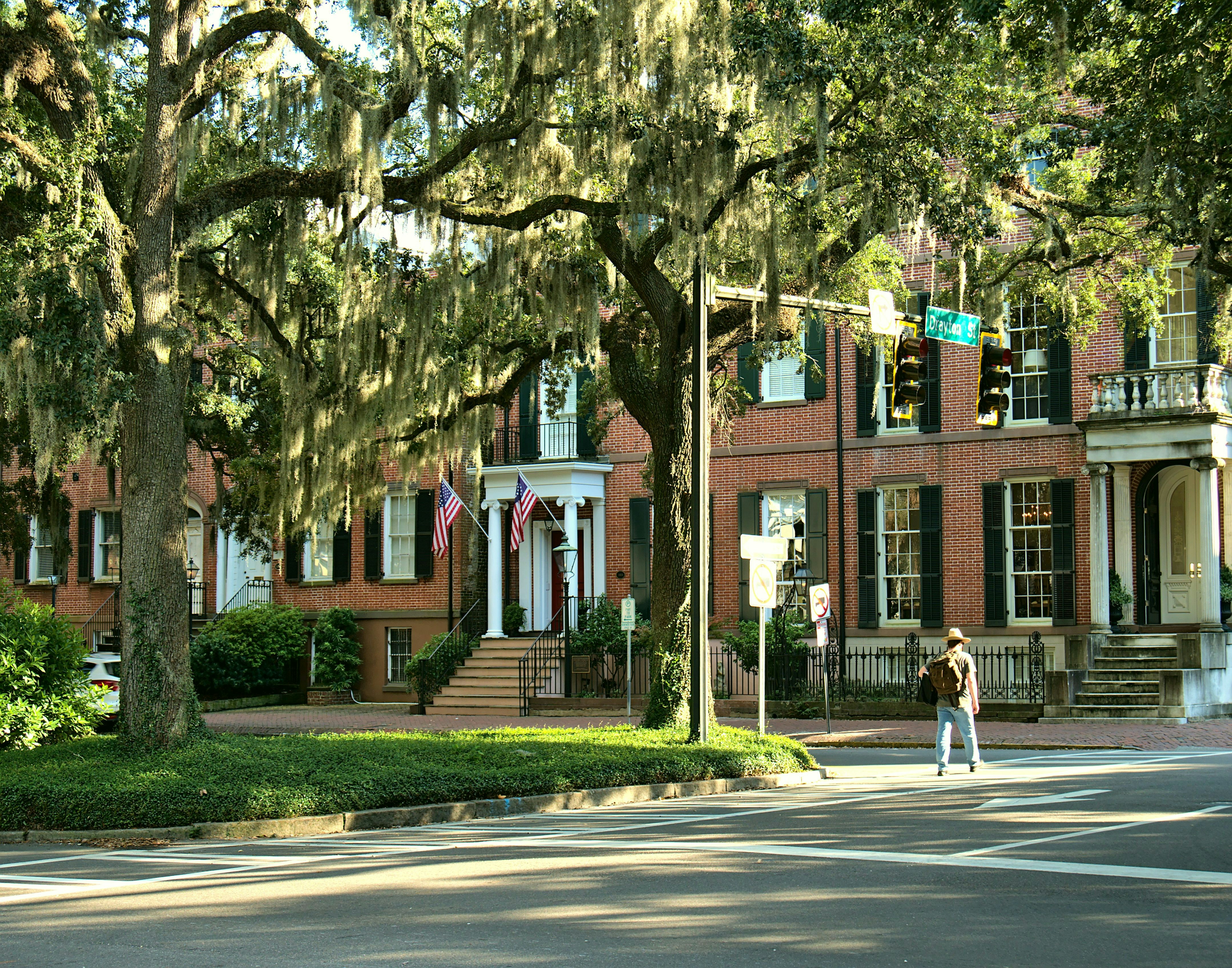 A sun-drenched street in a historic Savannah neighborhood, lined with elegant homes and oak trees with Spanish moss, representing a desirable residential property.