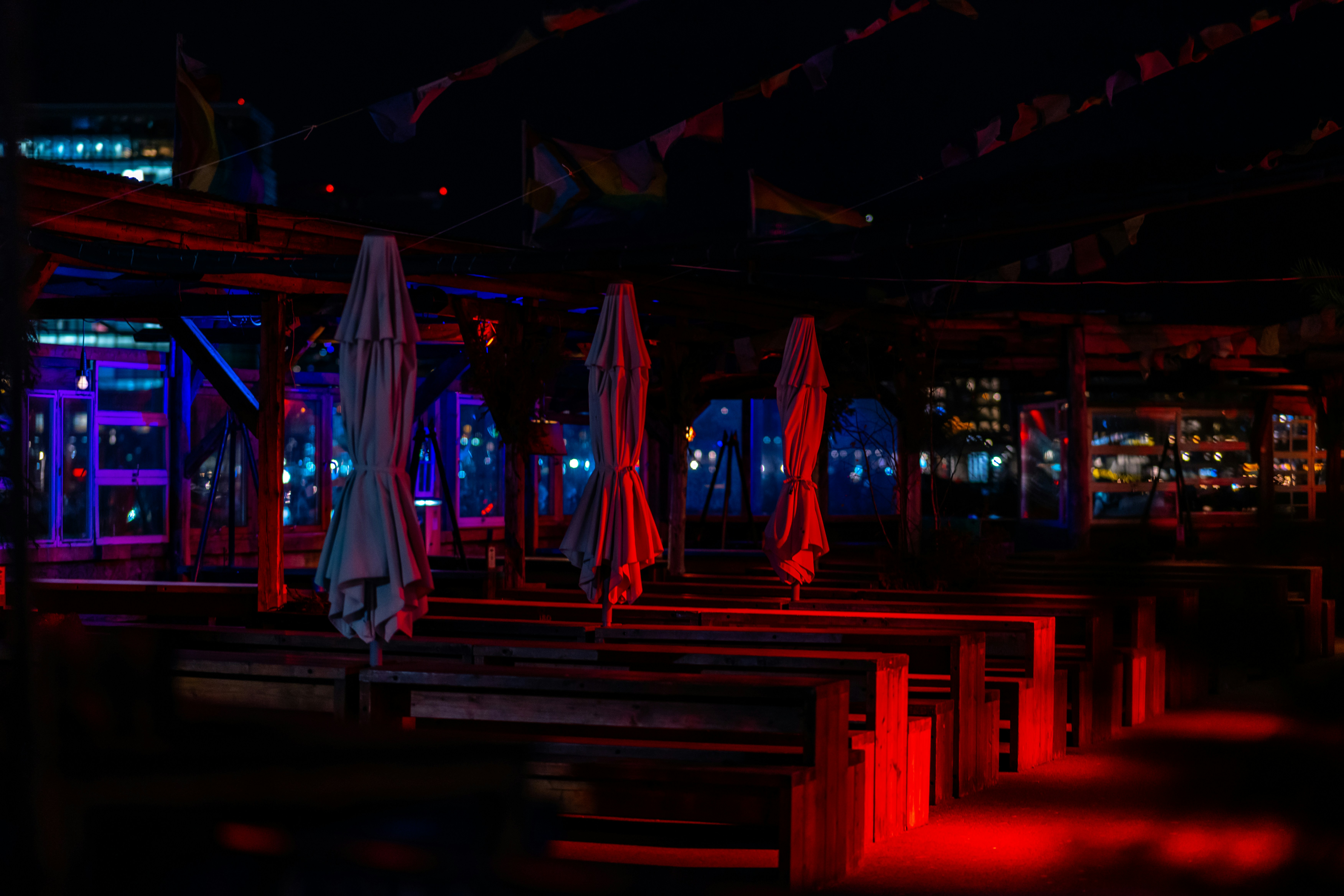 Bar tables and umbrellas lit red at night