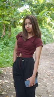 A woman standing on a dirt road in a forest