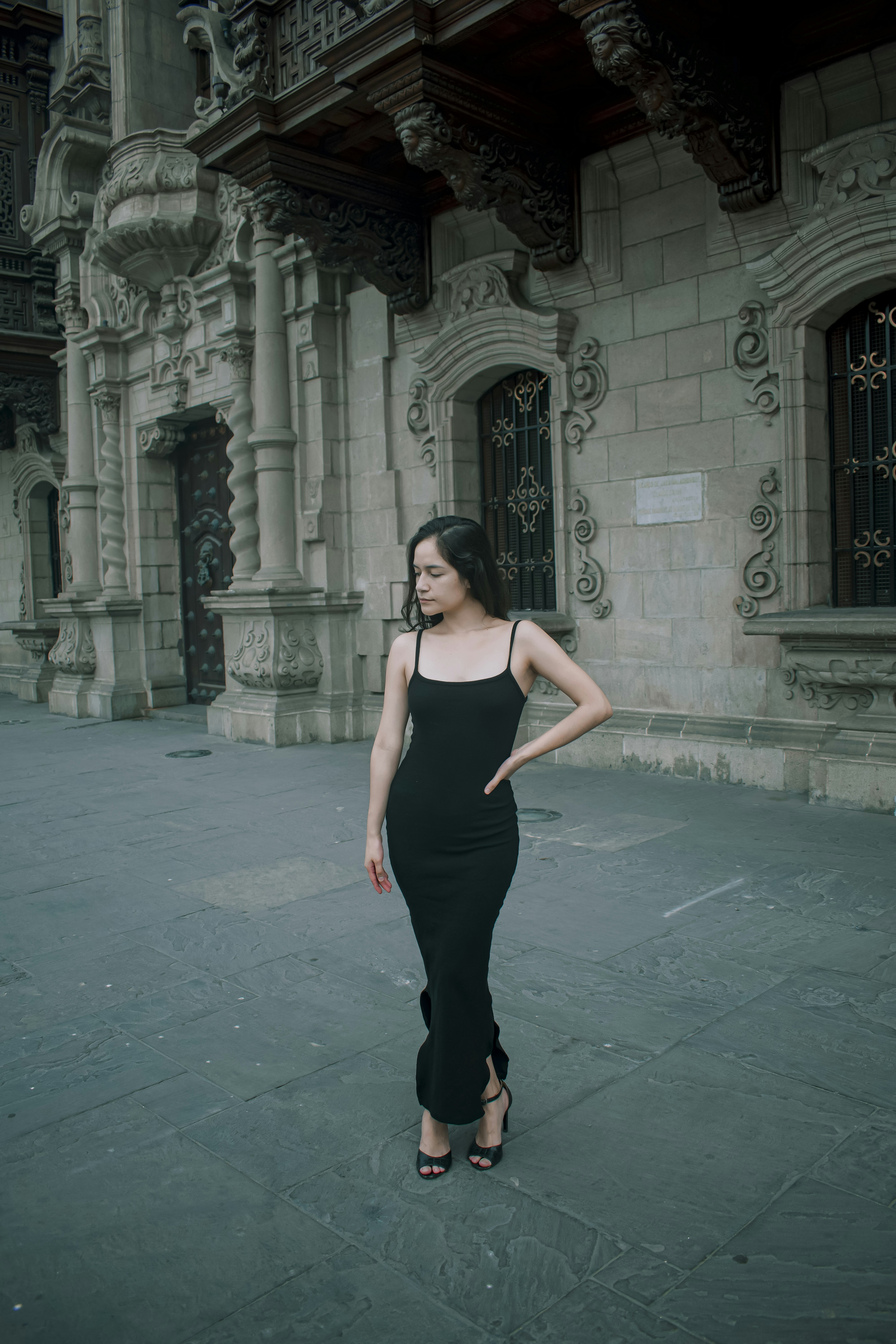 A woman in a black dress standing in front of a building photo – Free ...
