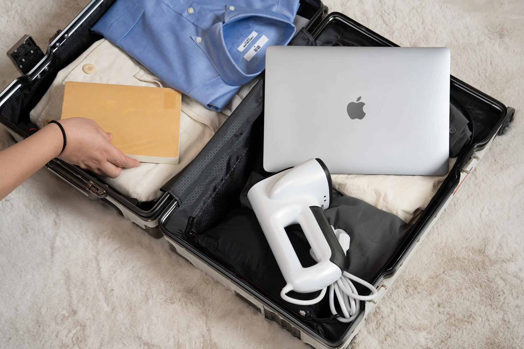 Open suitcase packed with clothing and business travel essentials