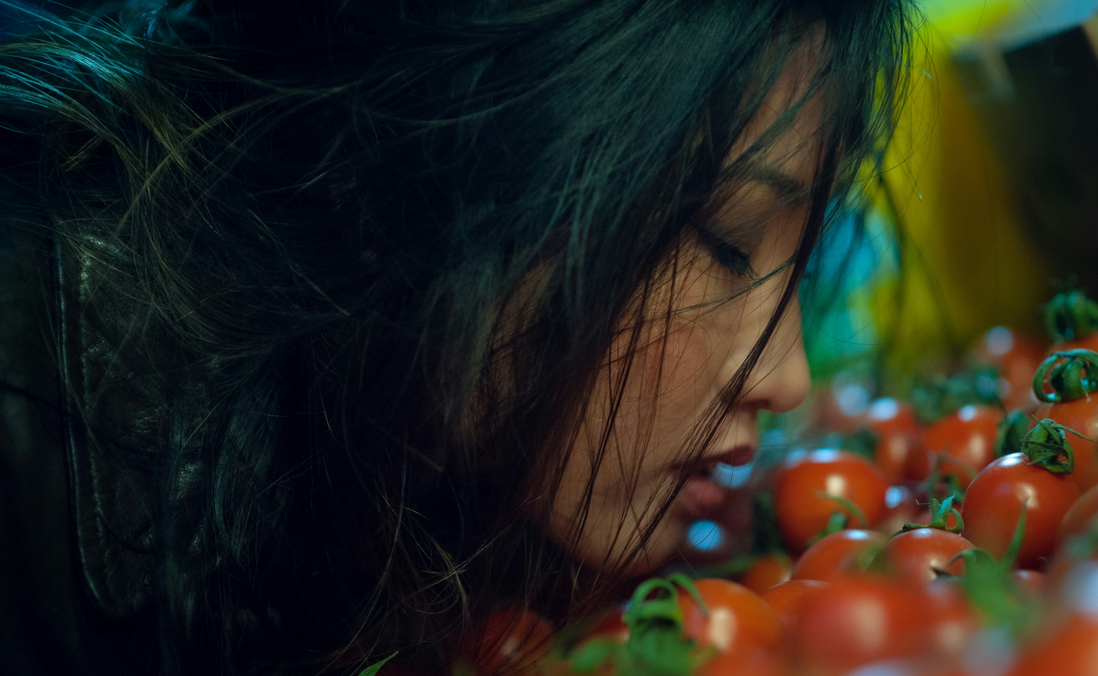 A woman looking at a bunch of tomatoes