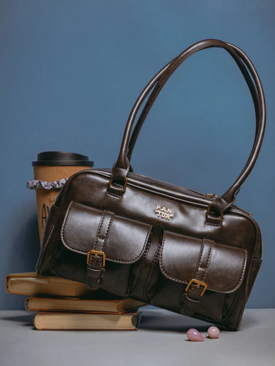 A brown purse sitting on top of a stack of books