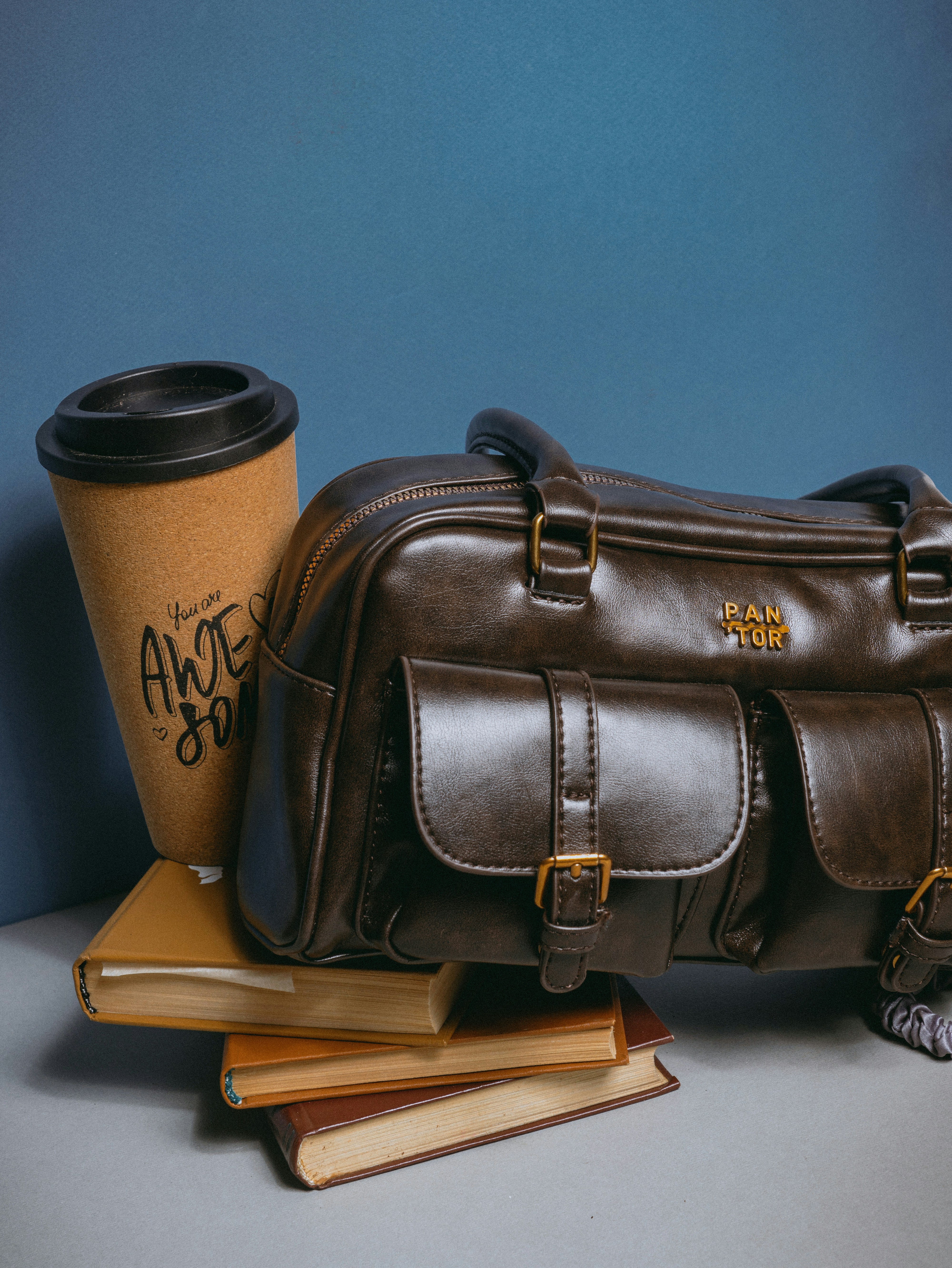 A brown leather bag and a coffee cup on a table