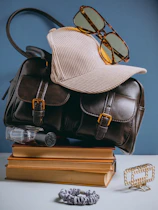 A hat, glasses, a book, and a purse sitting on top of a