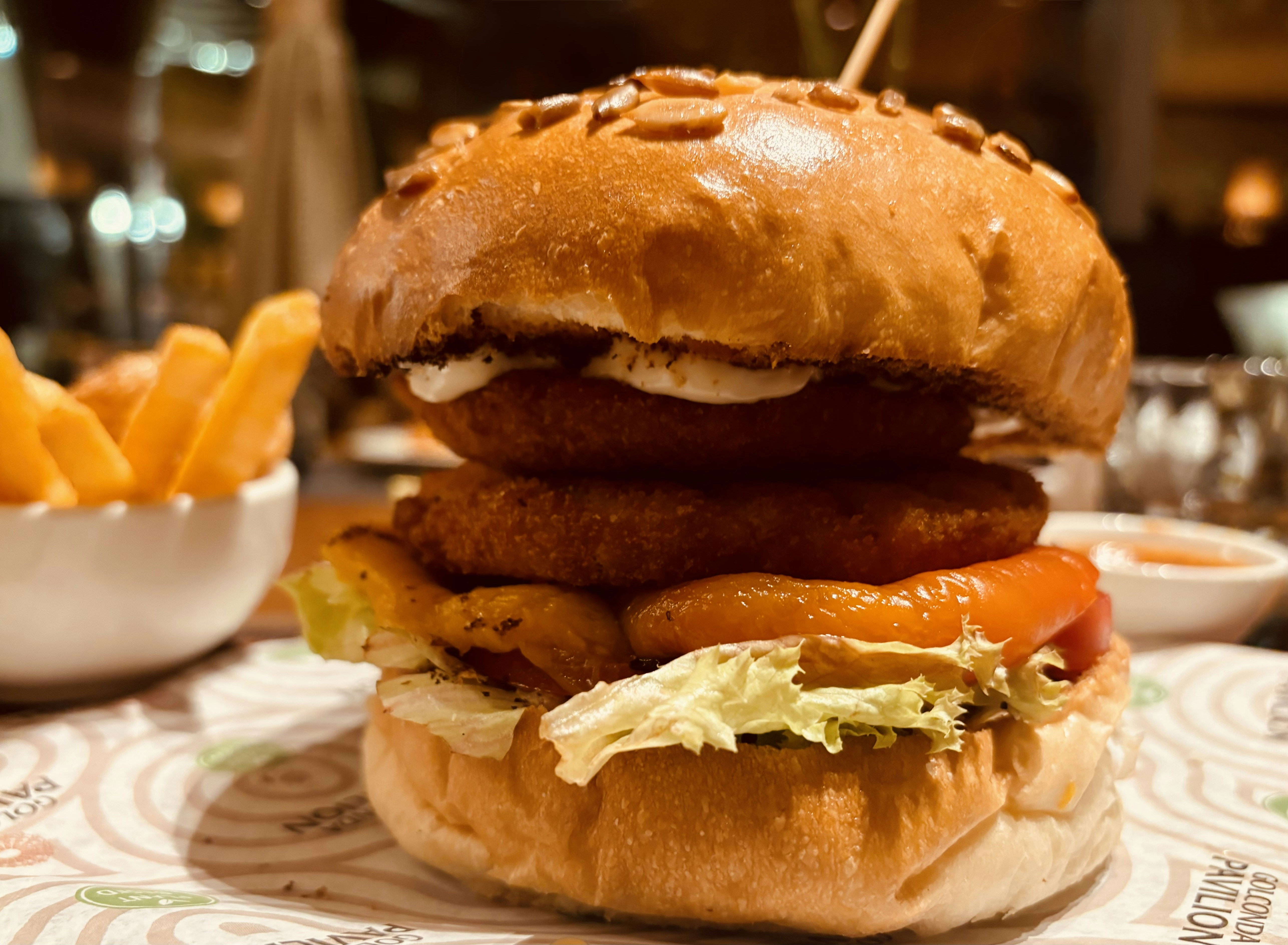 Tall gourmet beef burger with melted cheese, fresh lettuce and tomato in a toasted brioche bun, fries on the side