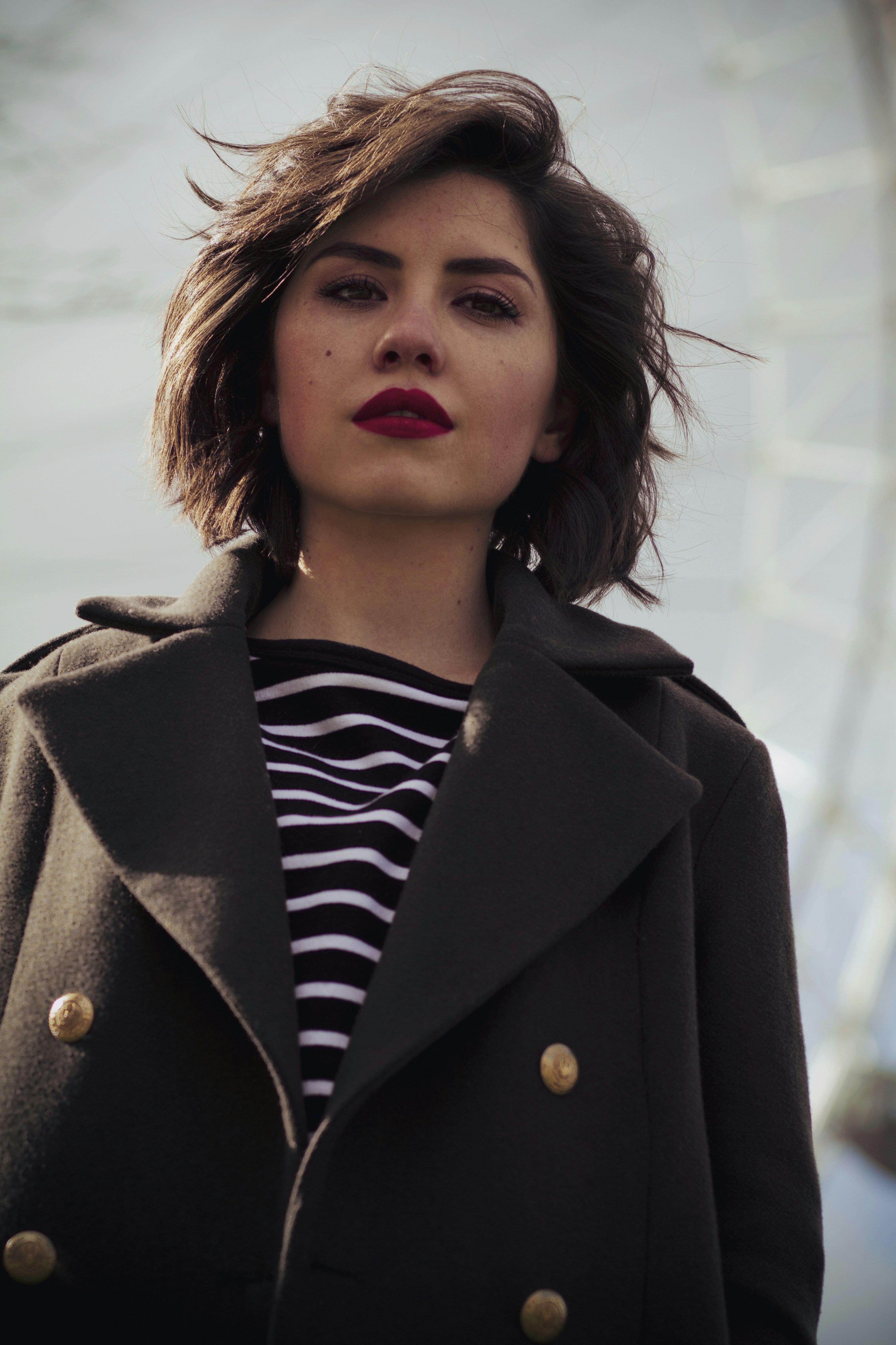 Eine Frau trägt einen Mantel und ein gestreiftes Hemd