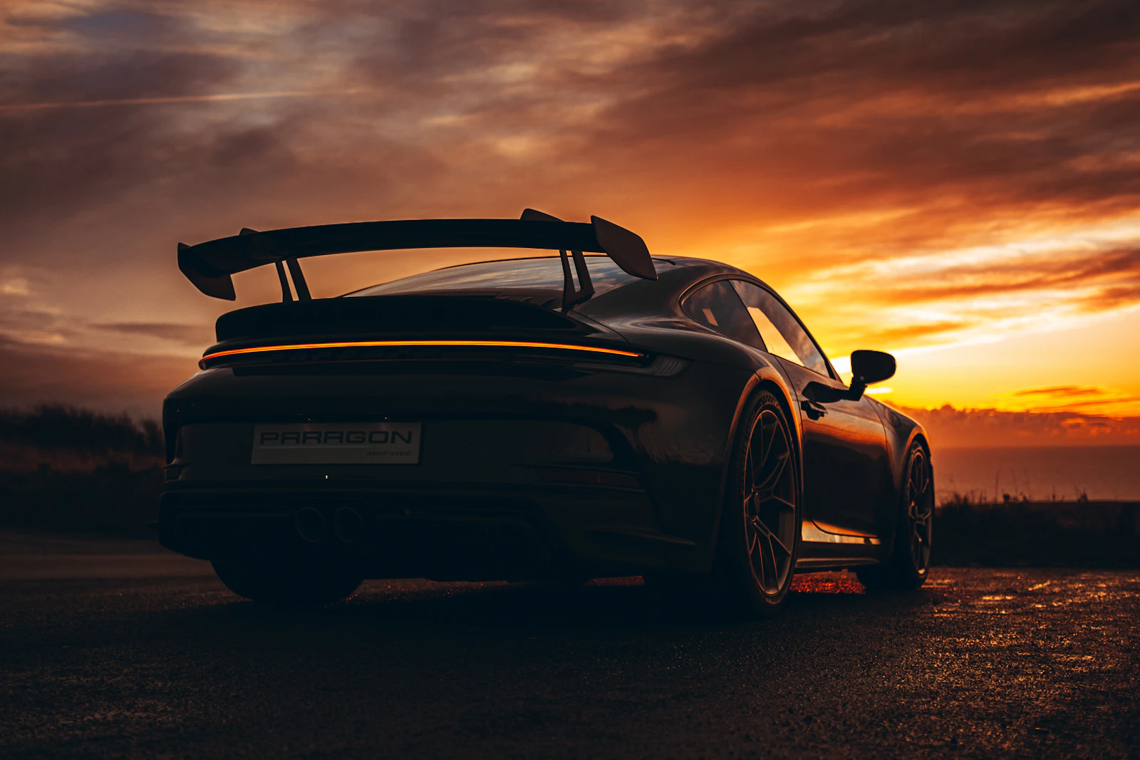 Dark Porsche 911 GT3 silhouetted against an orange sunset