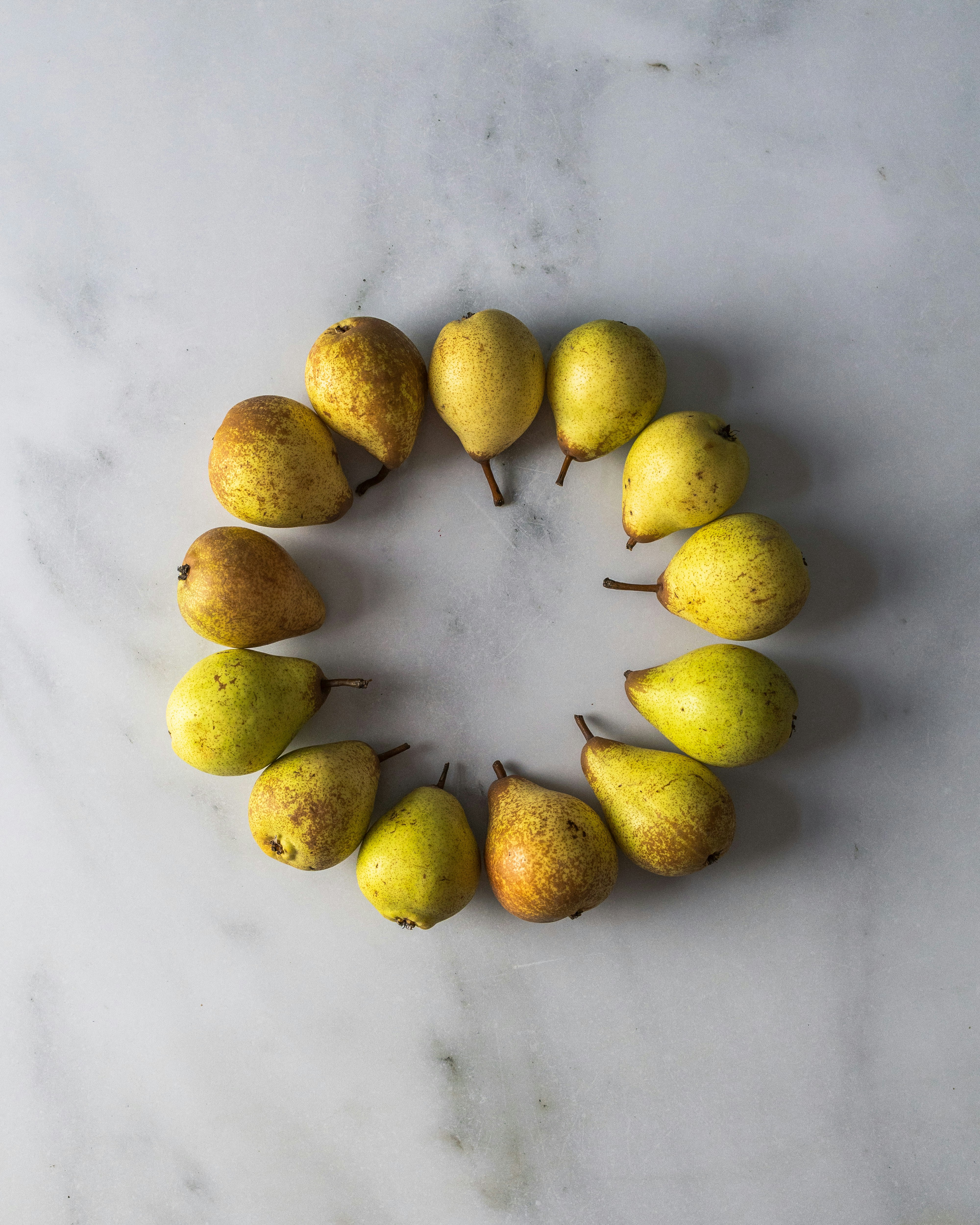 Pears arranged in a circle on a marble surface
