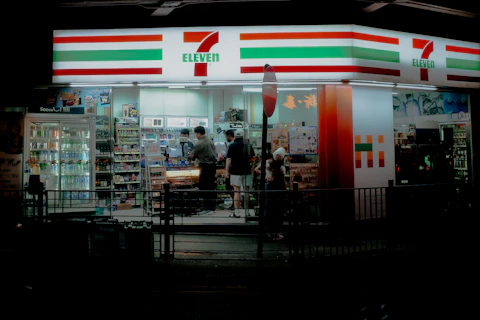 A convenience store at night with people standing outside